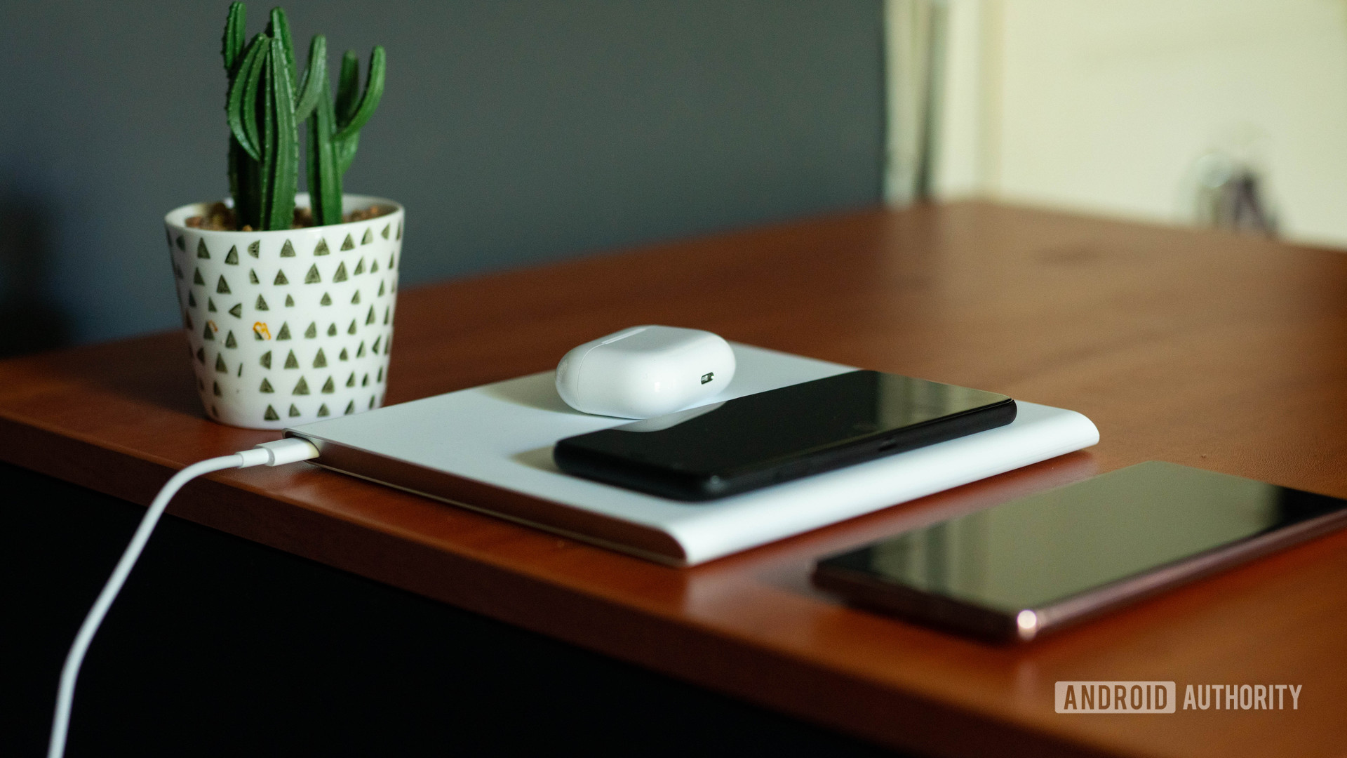 Xiaomi Mi 20W Smart Tracking Wireless Charging Pad with phones and earphones on it with the cable on show