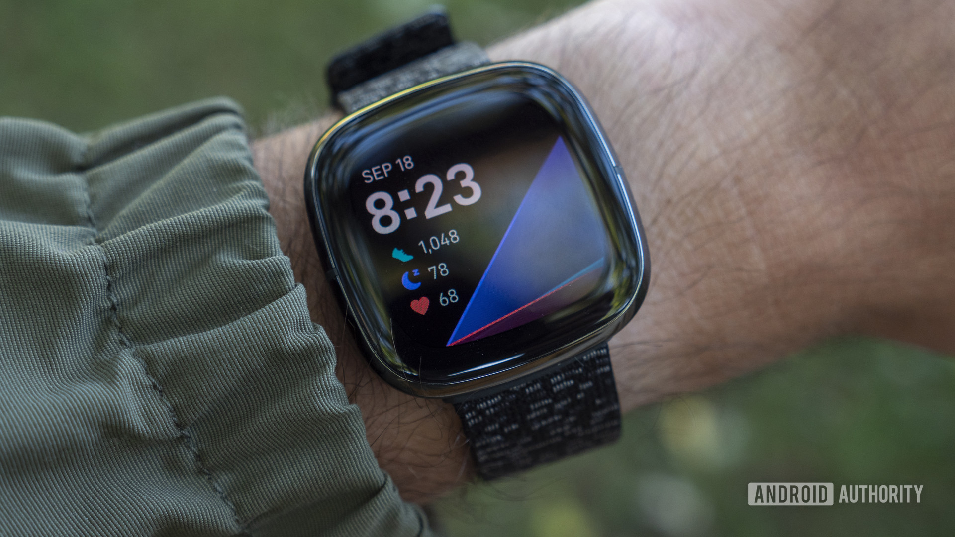 Bilekte ekranı ve saati gösteren Fitbit Sense.