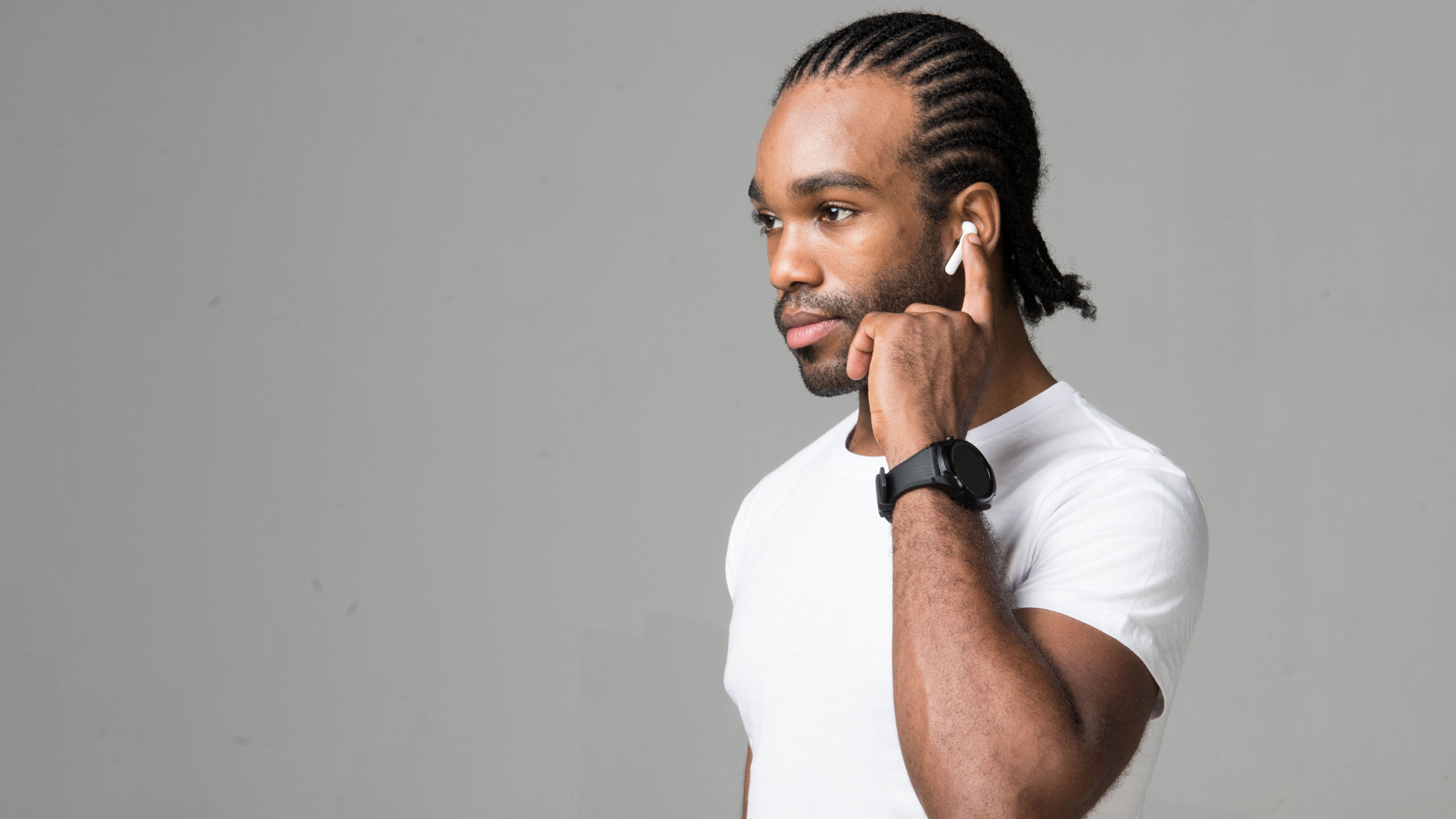 A photo of a man earing the Mobvoi TicPods 2 Pro Plus, with a finger raised to control music playback on the left earphone.