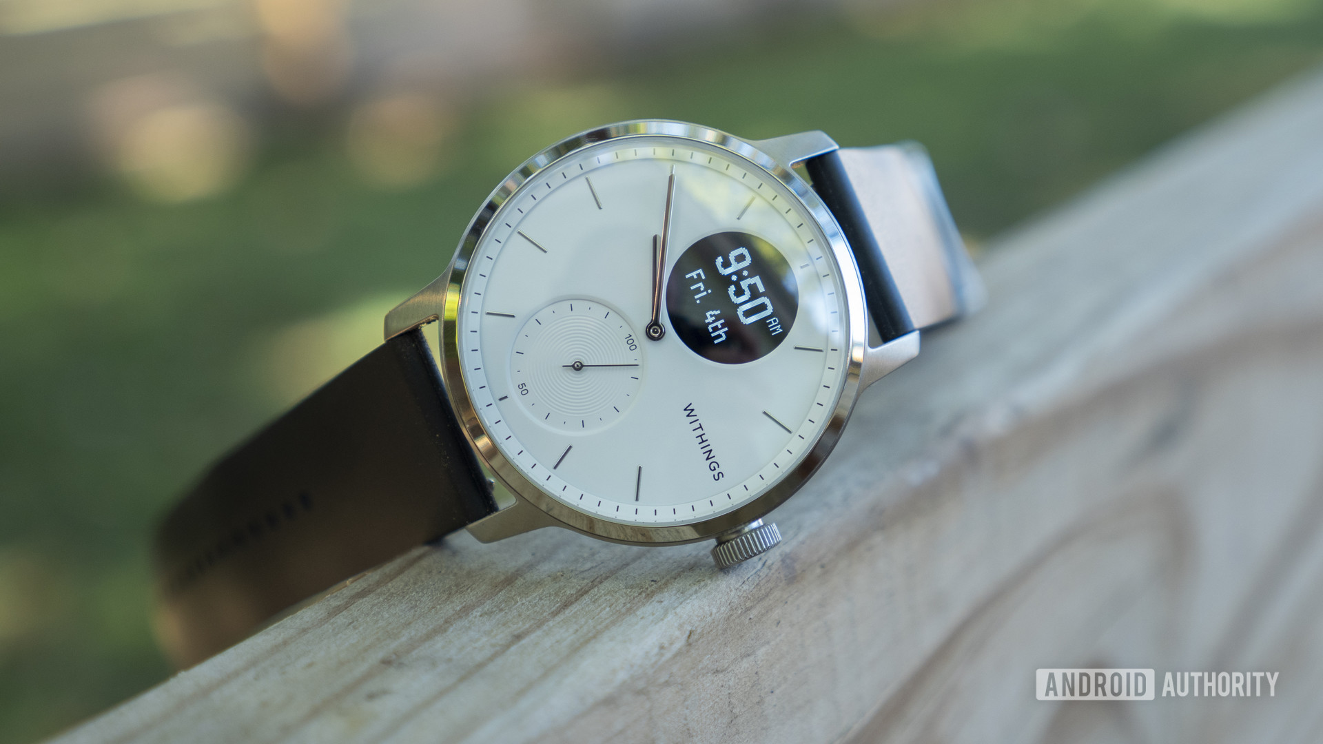 A Withings ScanWatch rests on its side on a wooden ledge.