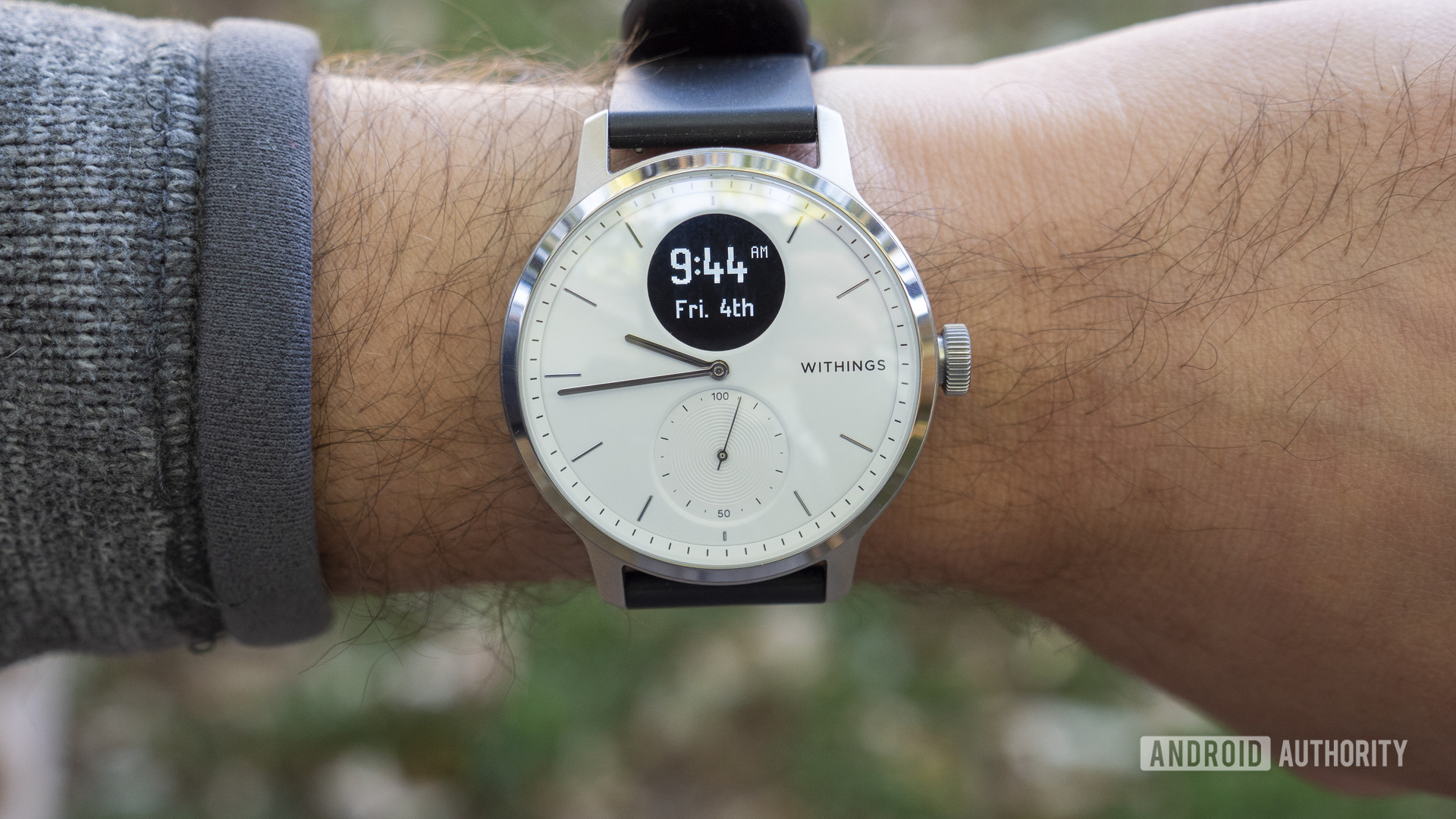A user models the Withings Scanwatch on their wrist, displaying the device's clock face.