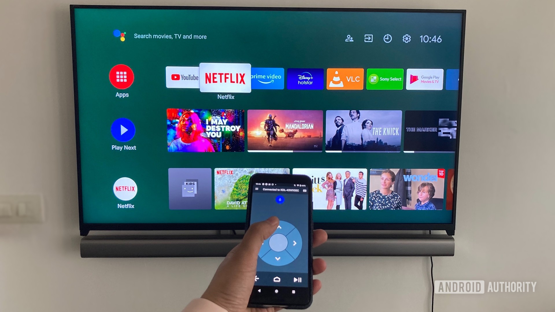 Android TV'nin önündeki bir akıllı telefondaki Android TV Uzaktan kumanda uygulamasını gösteren resim