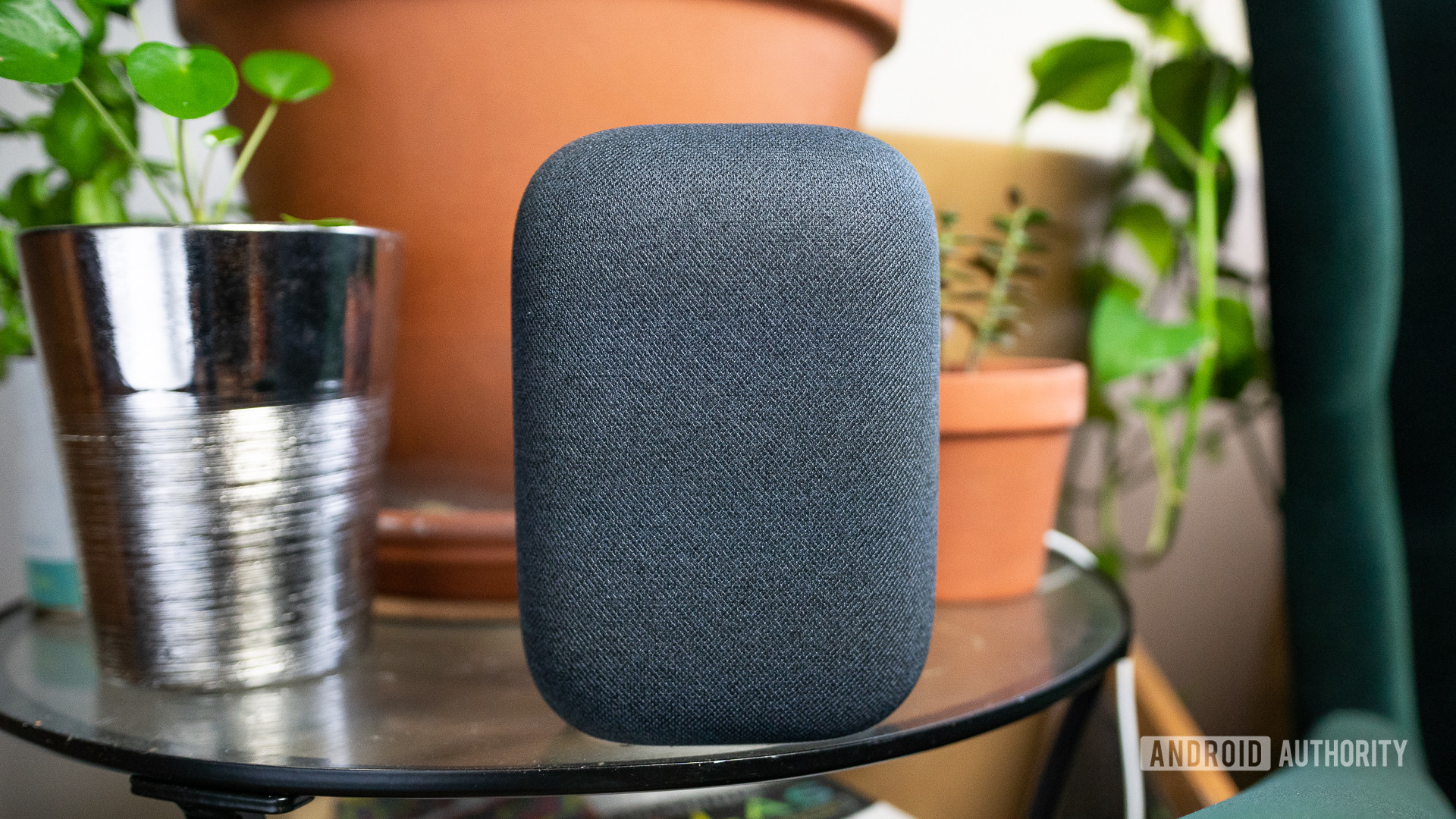 Google Nest Audio is displayed on a glass table with plants