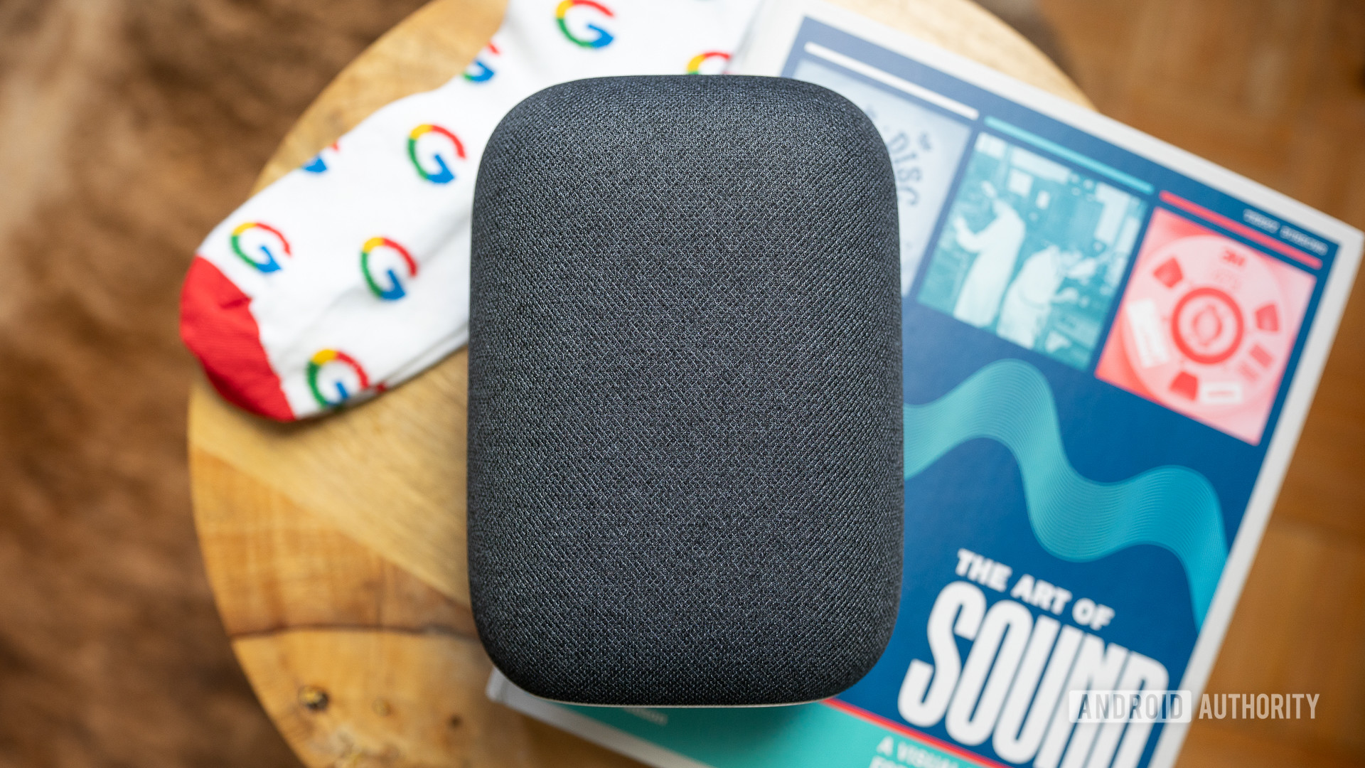 Google Nest Audio on top of coffeetable with a book and pair of Google socks