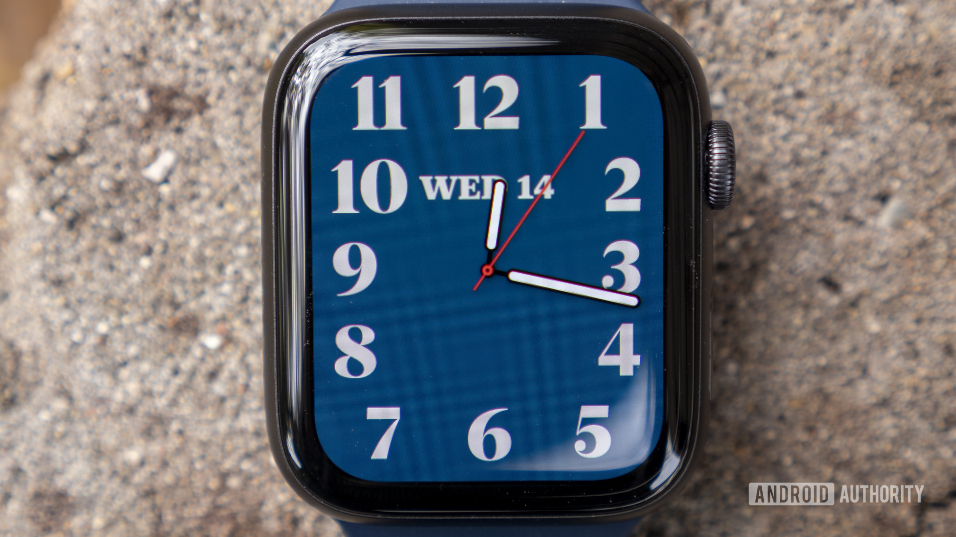 An Apple Watch Series 6 rests on stone displaying a standard analog watch face