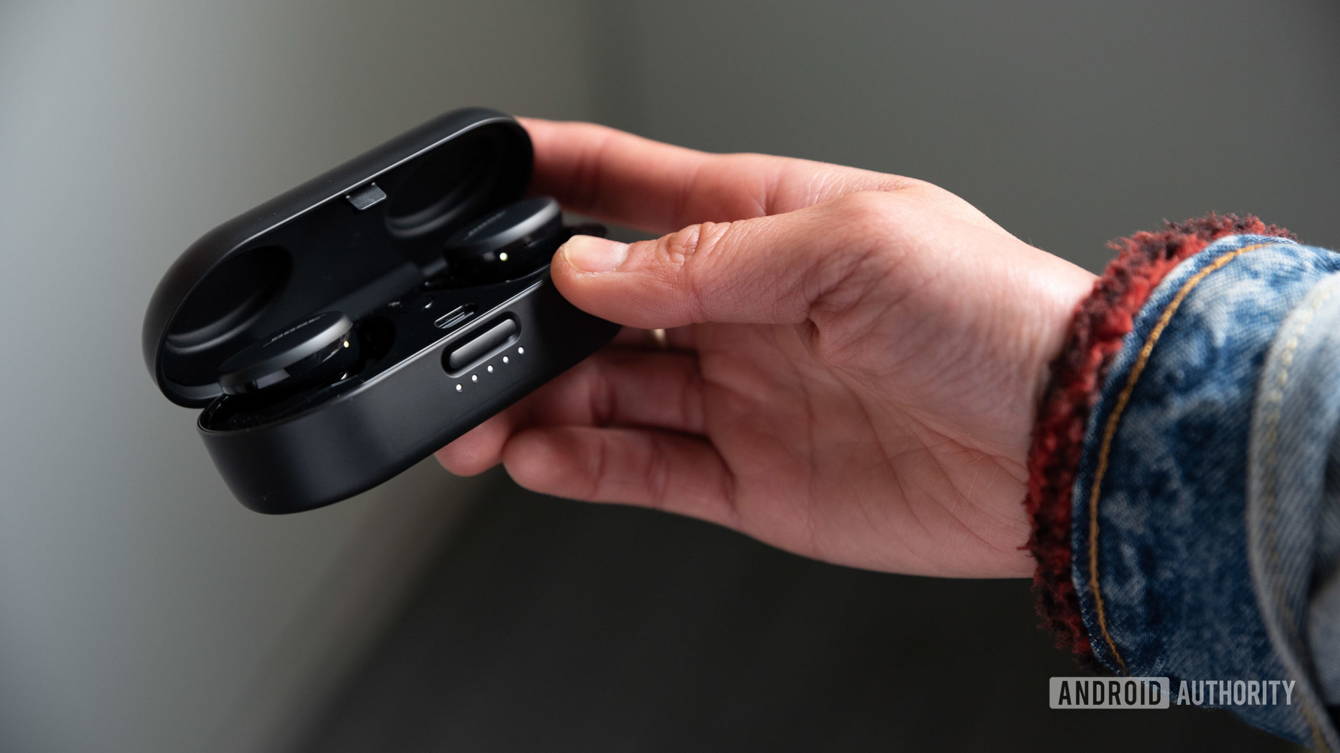 A woman opens the Bose Sport Earbuds charging case with one hand.