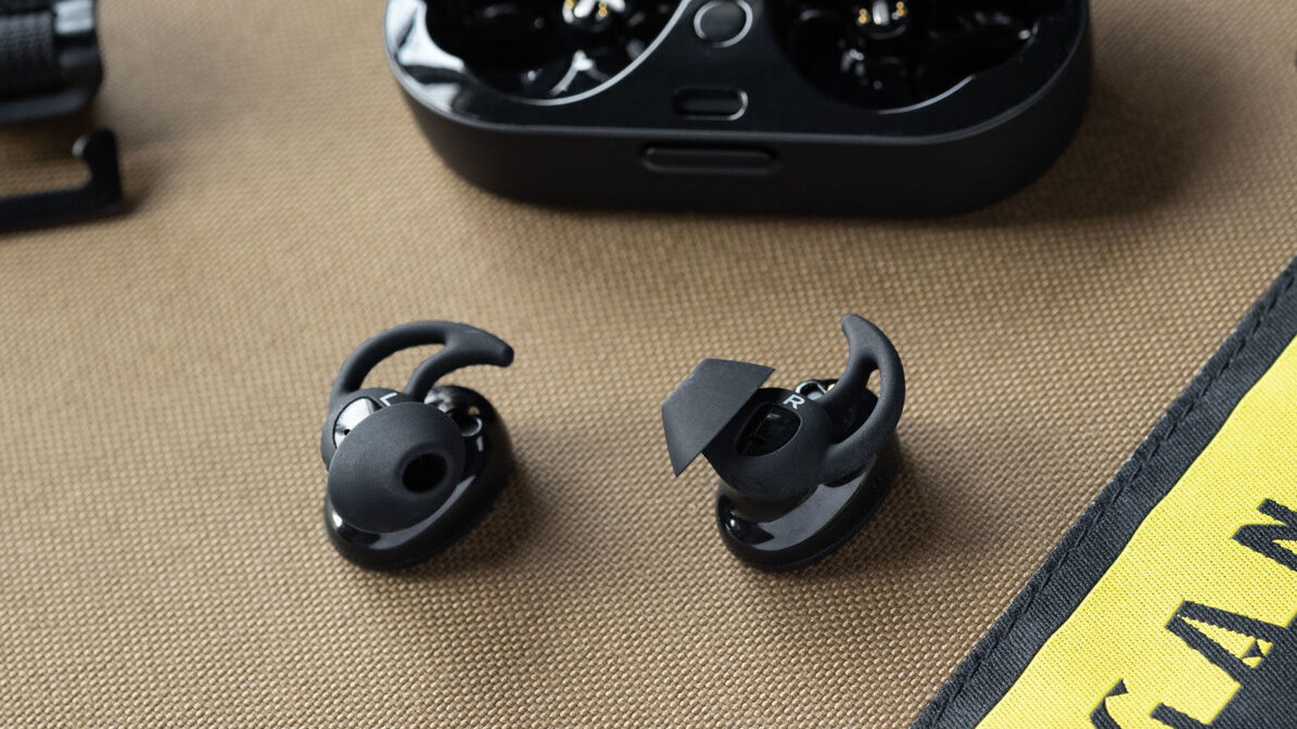 The Bose Sport Earbuds true wireless workout earbuds outside of the open charging case; the earbuds are facing belly-up so the StayHear Max ear tips are in full view.