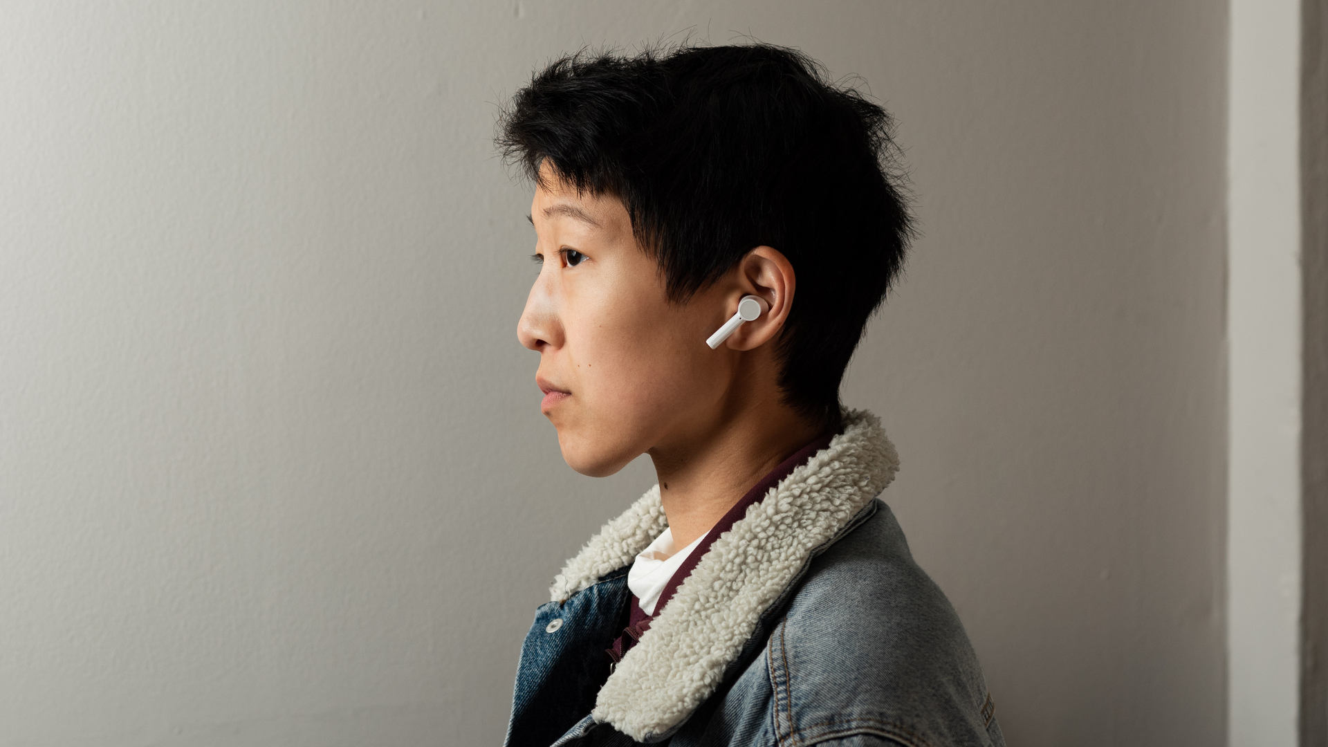 A woman wears the OnePlus Buds Z cheap true wireless earbuds in white to illustrate the buds' sizing.