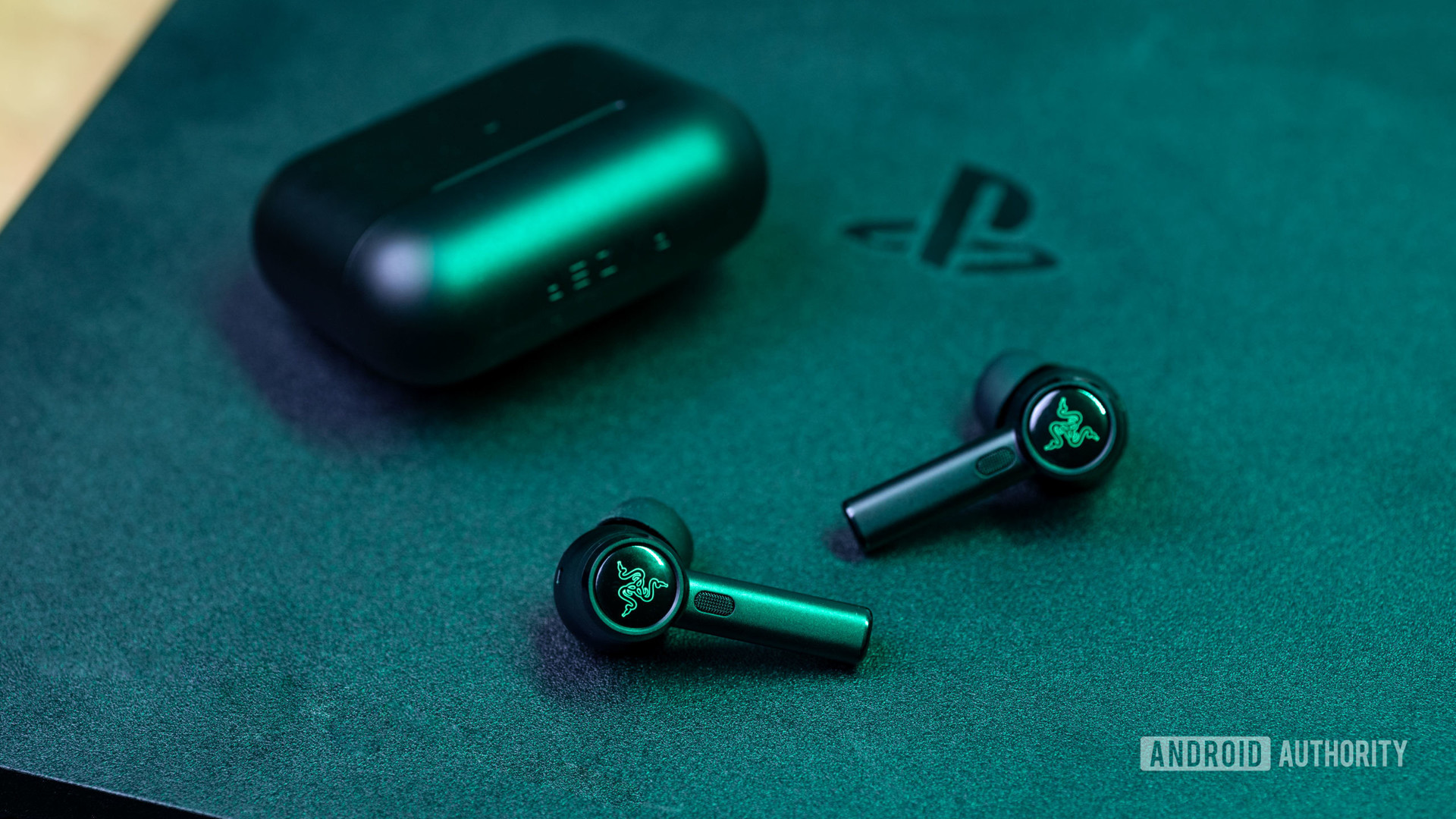 The Razer Hammerhead True Wireless Pro noise-cancelling true wireless earbuds on top of a PlayStation 4 gamgin console.