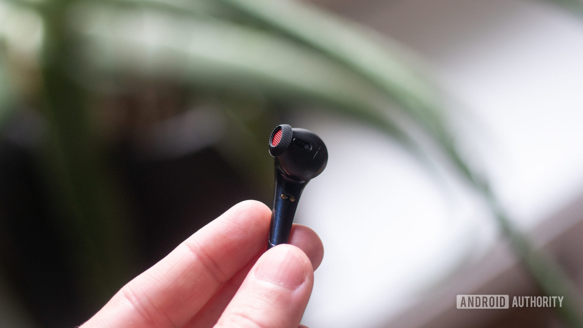 A hand holds the 1MORE Comfobuds earbud with the nozzle in full view.