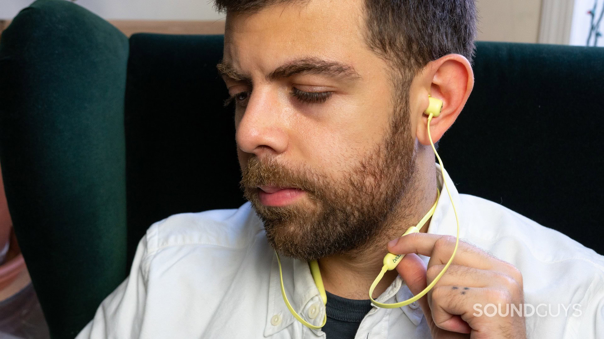 A man wears the Beats Flex wireless earbuds in yellow.