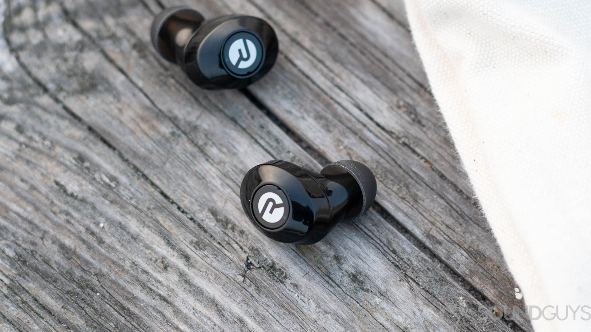 The Raycon E25 earbuds on a wood surface.