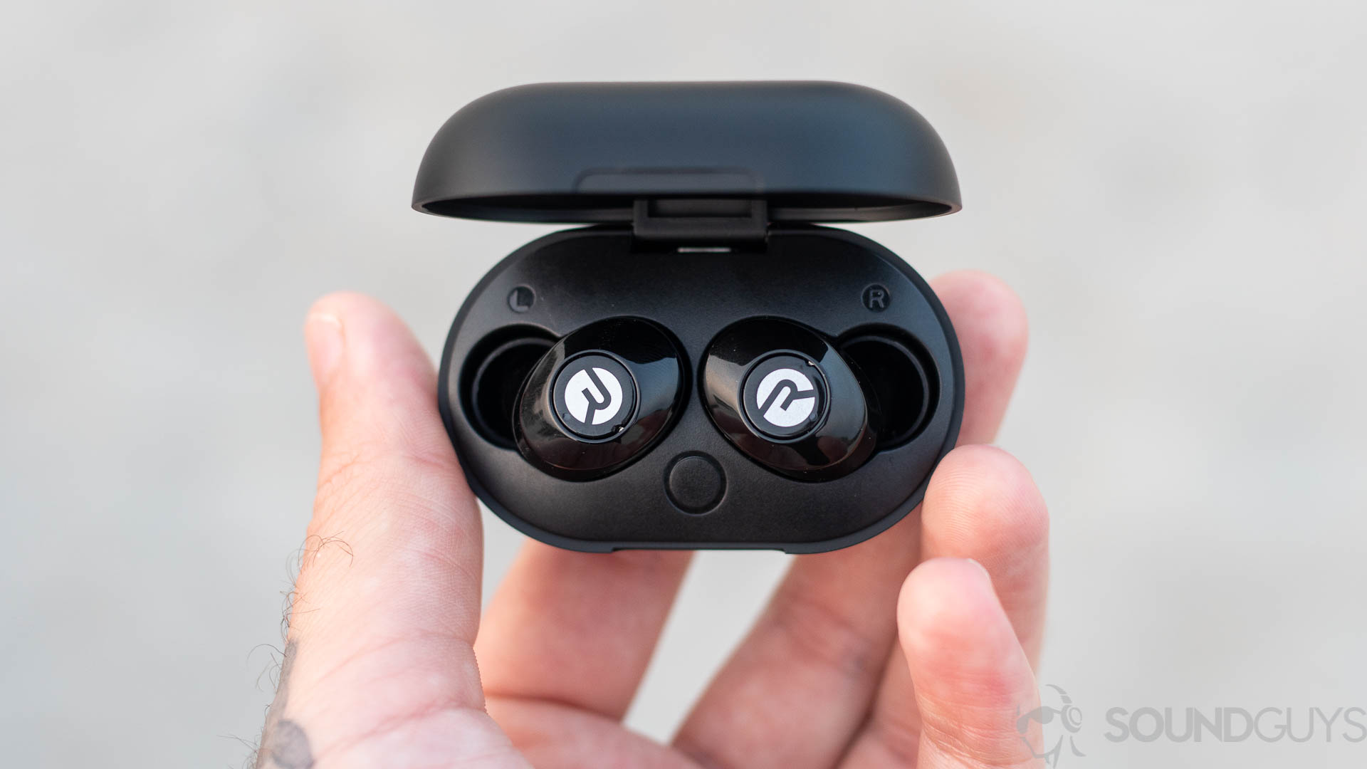 A man holds the Raycon E25 case open which reveals the true wireless earbuds.