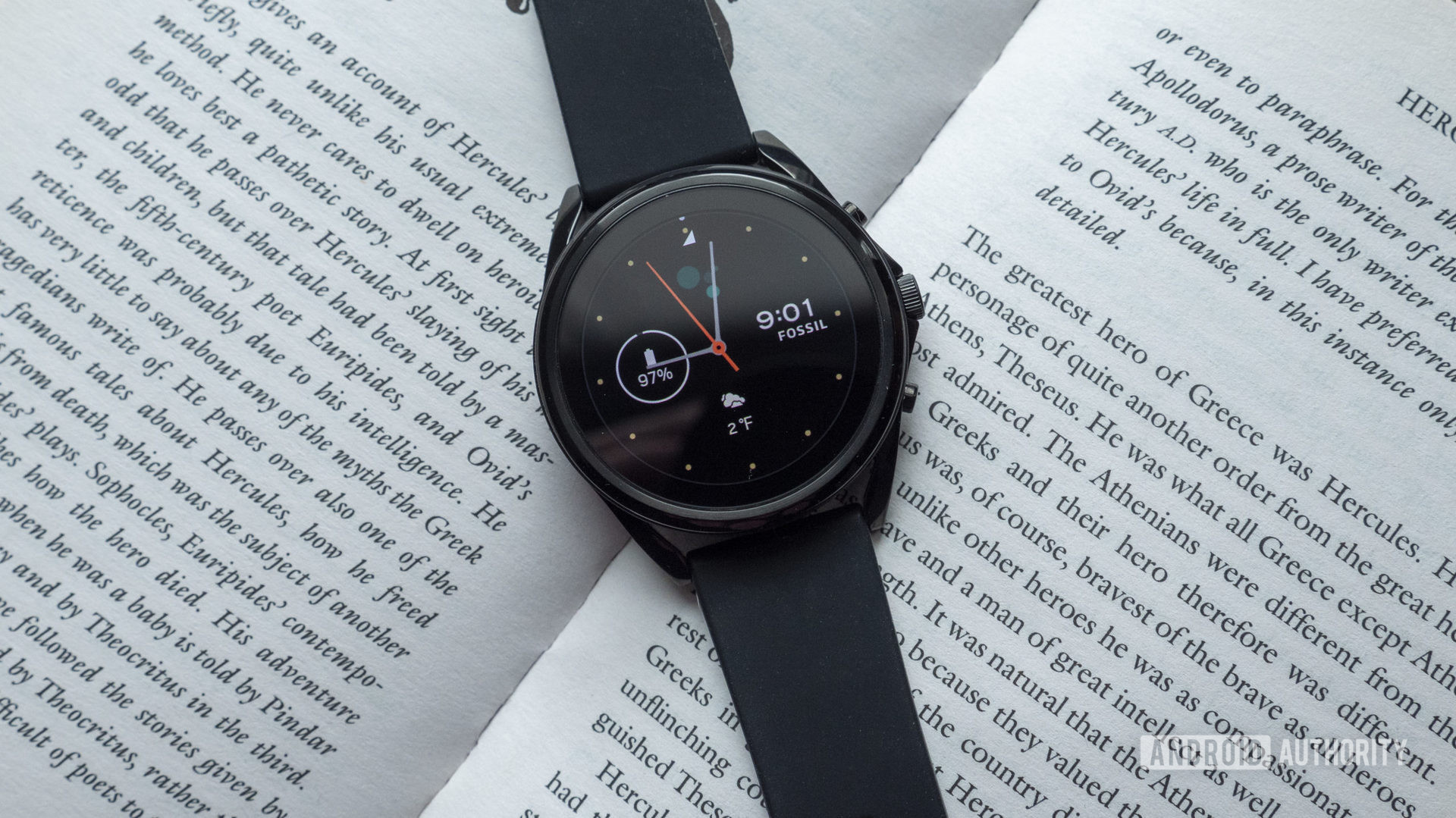 An older Wear OS device, a Fossil Gen 5, rests atop an open.