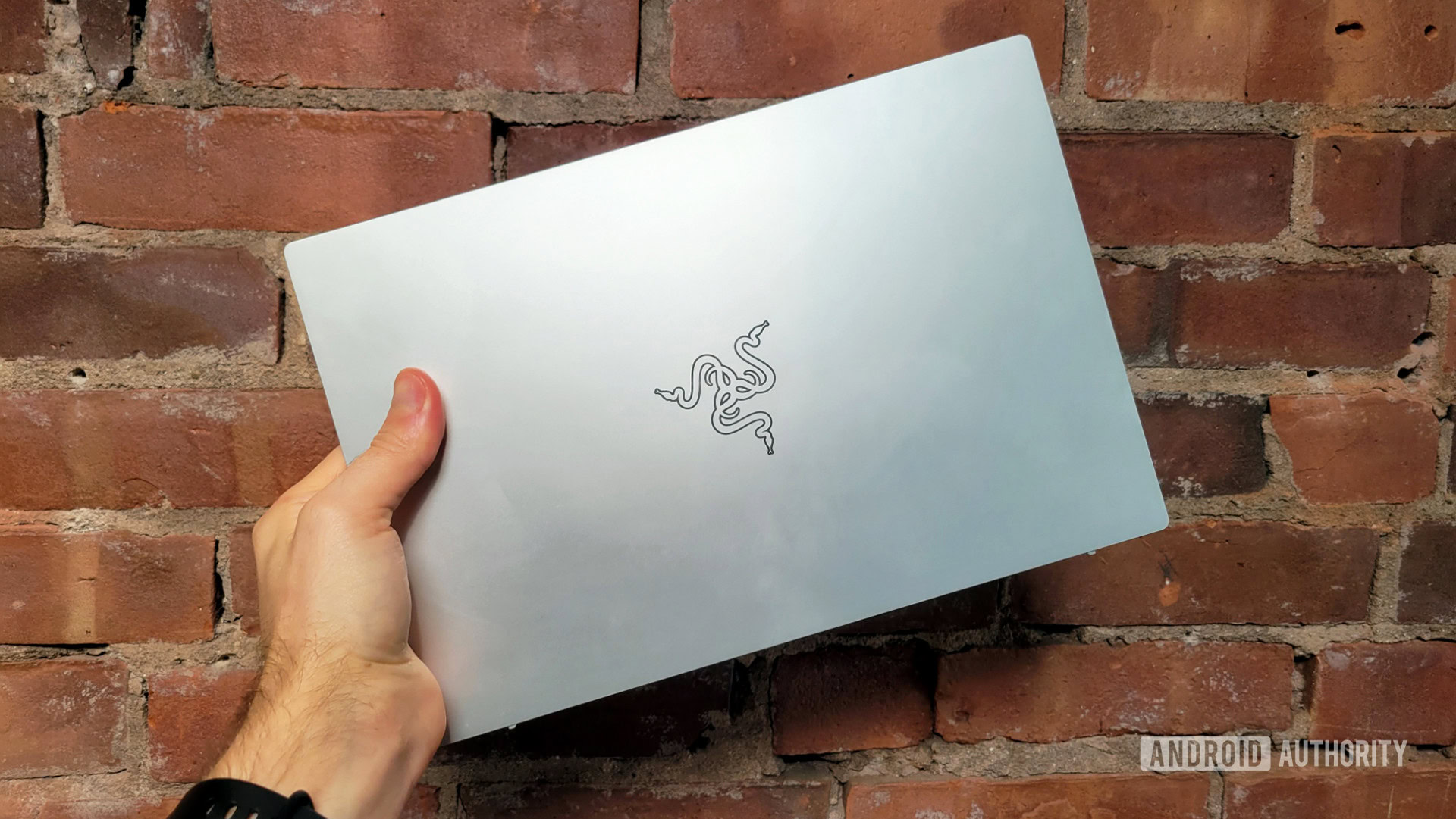 Razer Book 13 Review Closed In Hand Showing Razer Logo