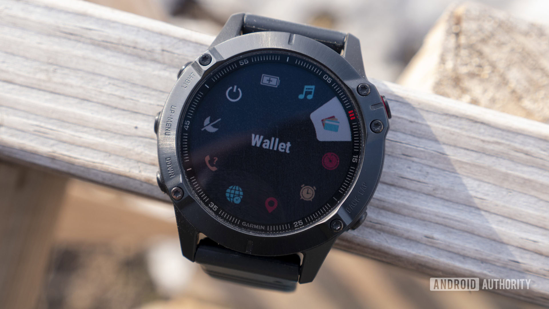 A Garmin Fenix 6 Pro rests on a wooden fence displaying a user's wallet.