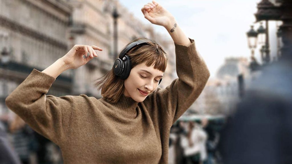 A woman wears the Anker Soundcore Life Q30 headphones while dancing in the street.
