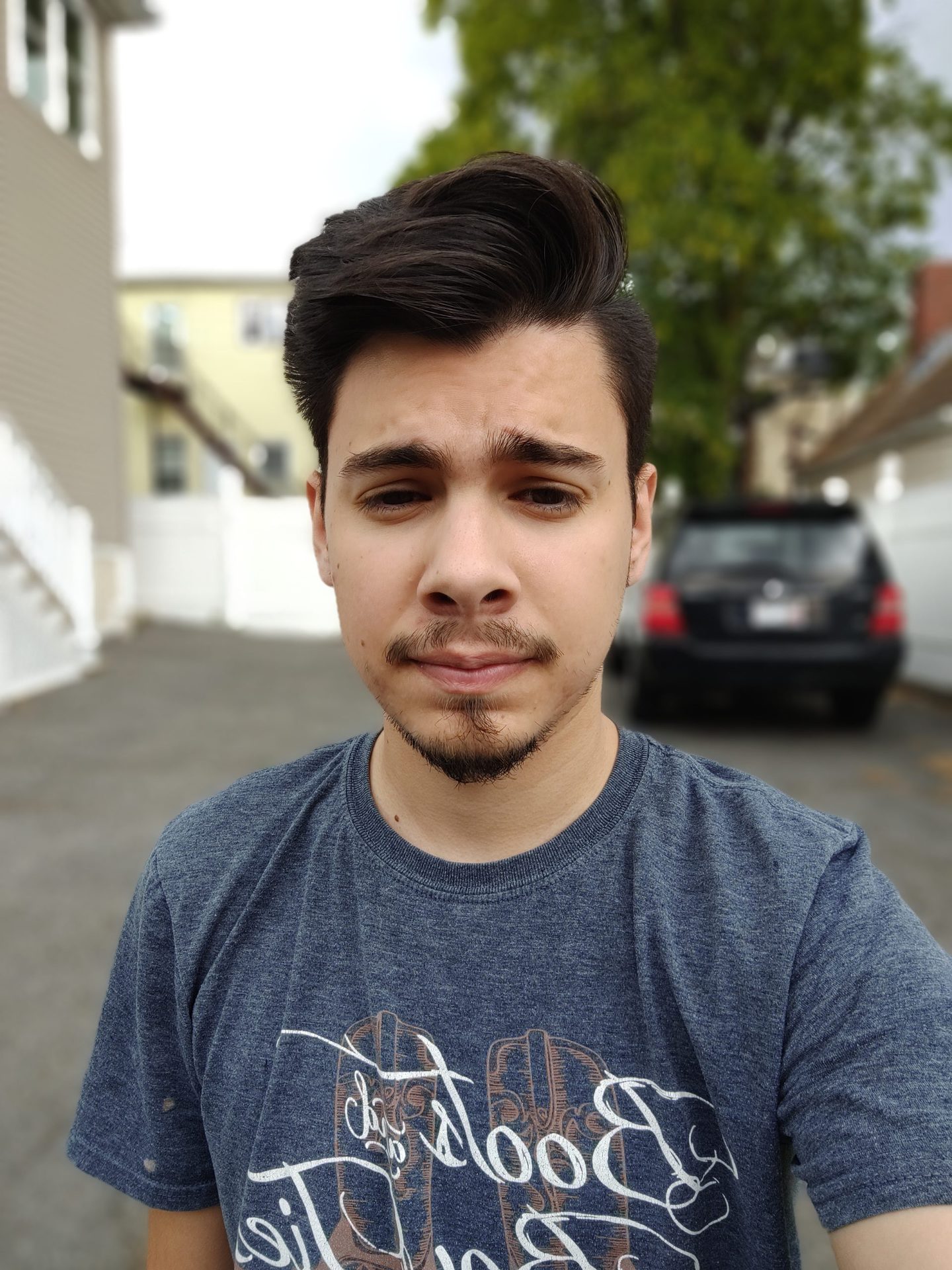 TCL 20 Pro 5G front-facing camera selfie shot of a dark-haired man in a gray tee outdoors in overcast lighting.
