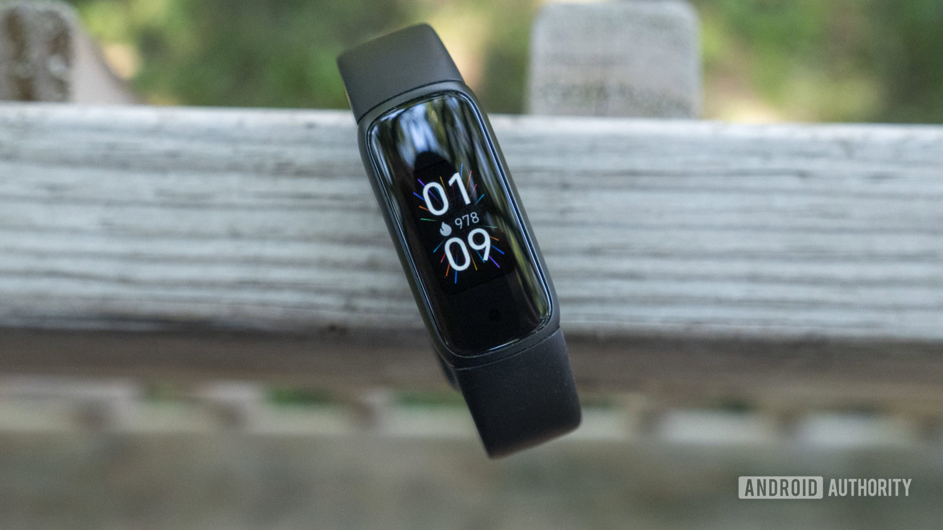 A Fitbit Luxe rests on a wooden fence post.