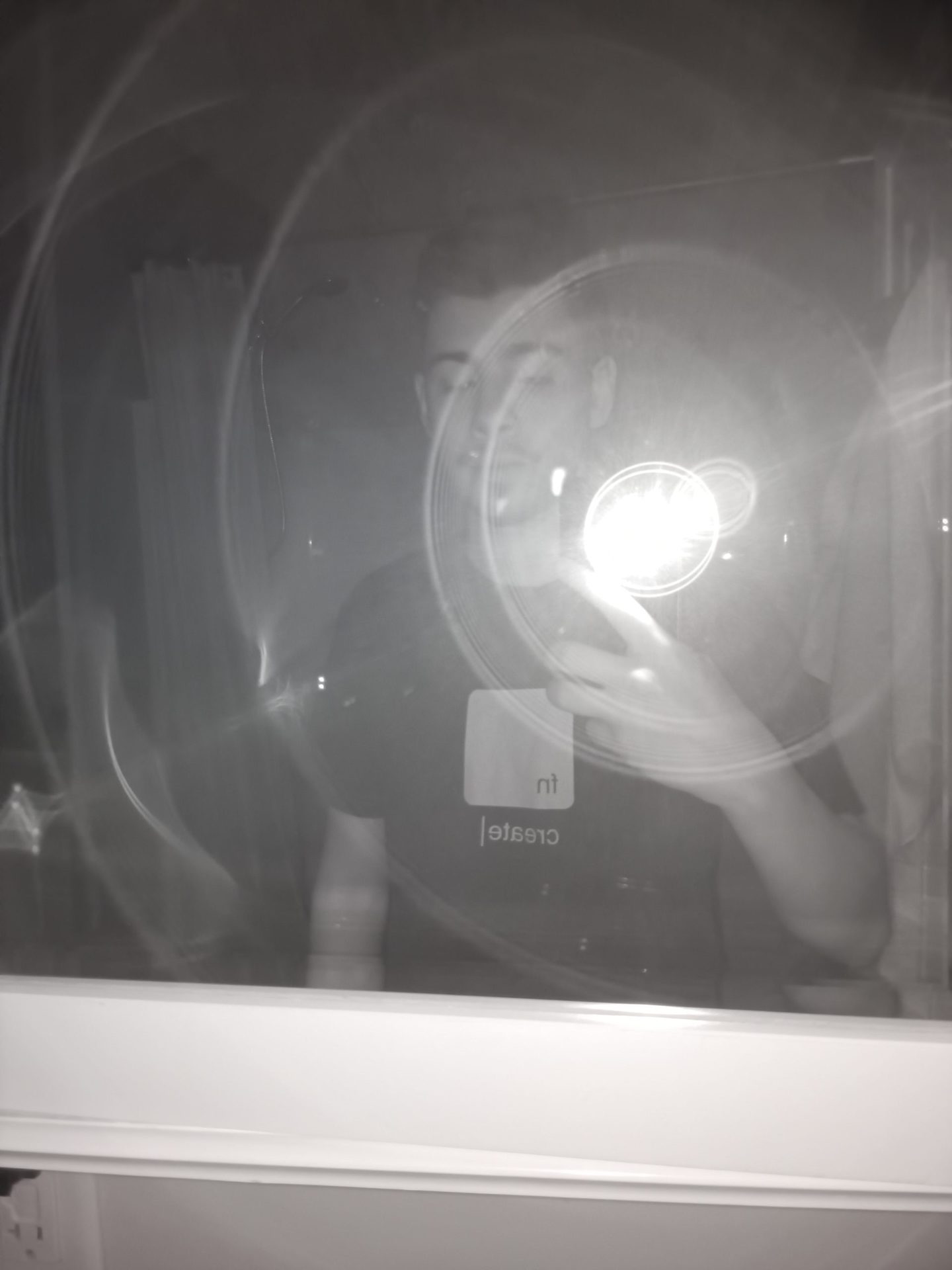 Ulefone Armor 11 5G Night Vision Camera Sample showing a picture of a man in a dark colored tshirt taking a photo in a mirror, with the flash reflecting.