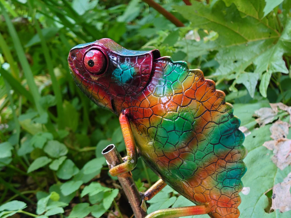 Sony Xperia 1 III camera 70mm shot of a colorful metal chameleon garden ornament in front of green leaves.