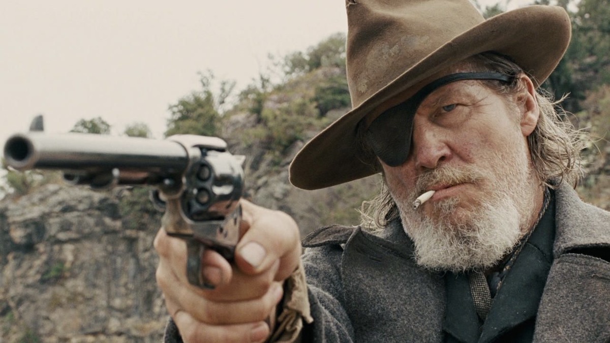 Jeff Bridges aims a pistol while smoking a cigarette in True Grit - best westerns on Netflix