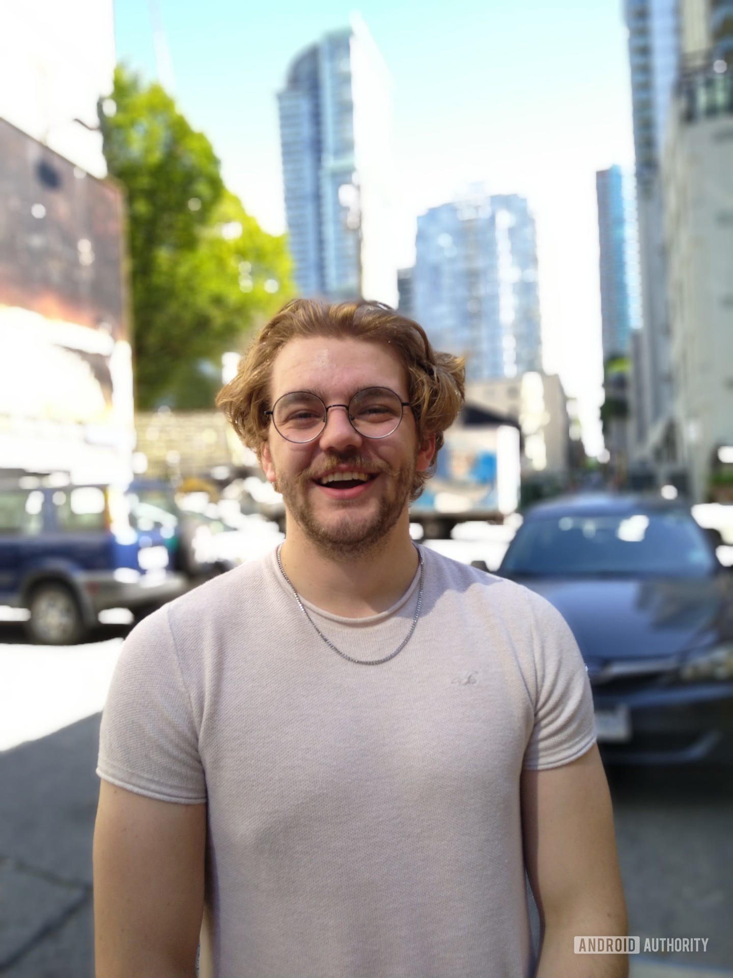 Cat S62 Pro Portrait photo of a man with wavy blond hair and a beard, wearing glasses and a white t-shirt.