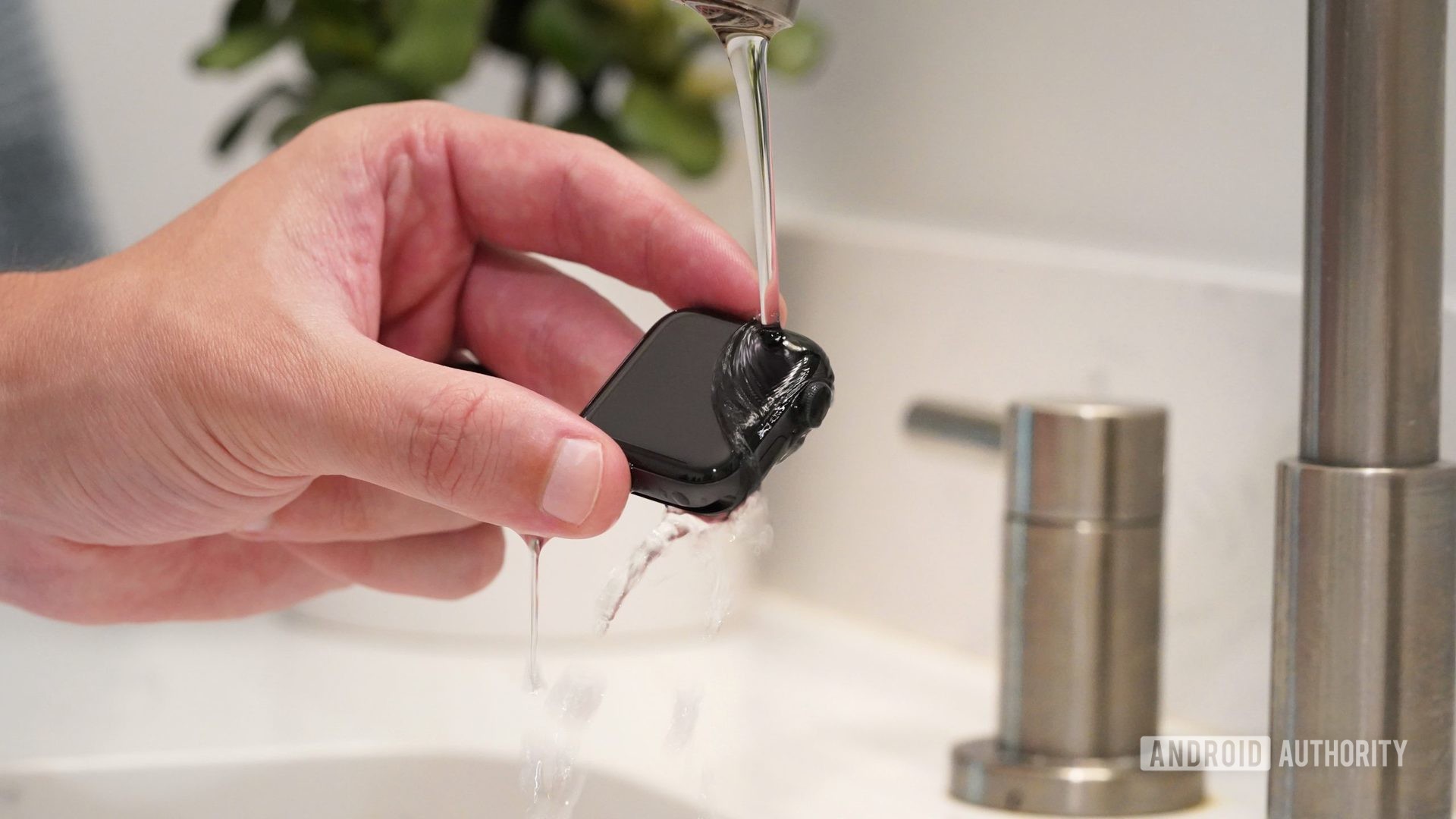 La mano masculina sostiene el Apple Watch Series 6 bajo un flujo bajo de agua tibia para limpiar el dispositivo.