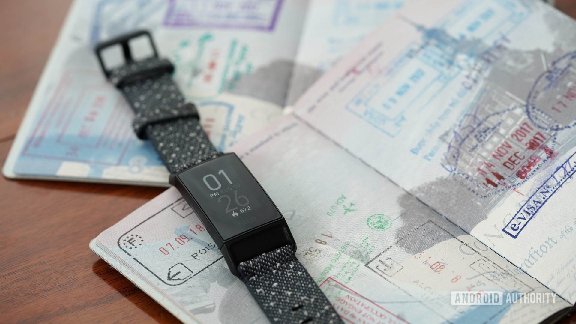 A Fitbit Charge 4 rests on open passports alluding to the ability to change the time on your Fitbit based on time zones.