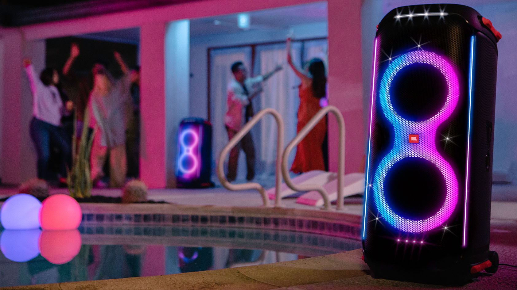 The JBL Partybox 710 speaker is poolside with people partying in the background.