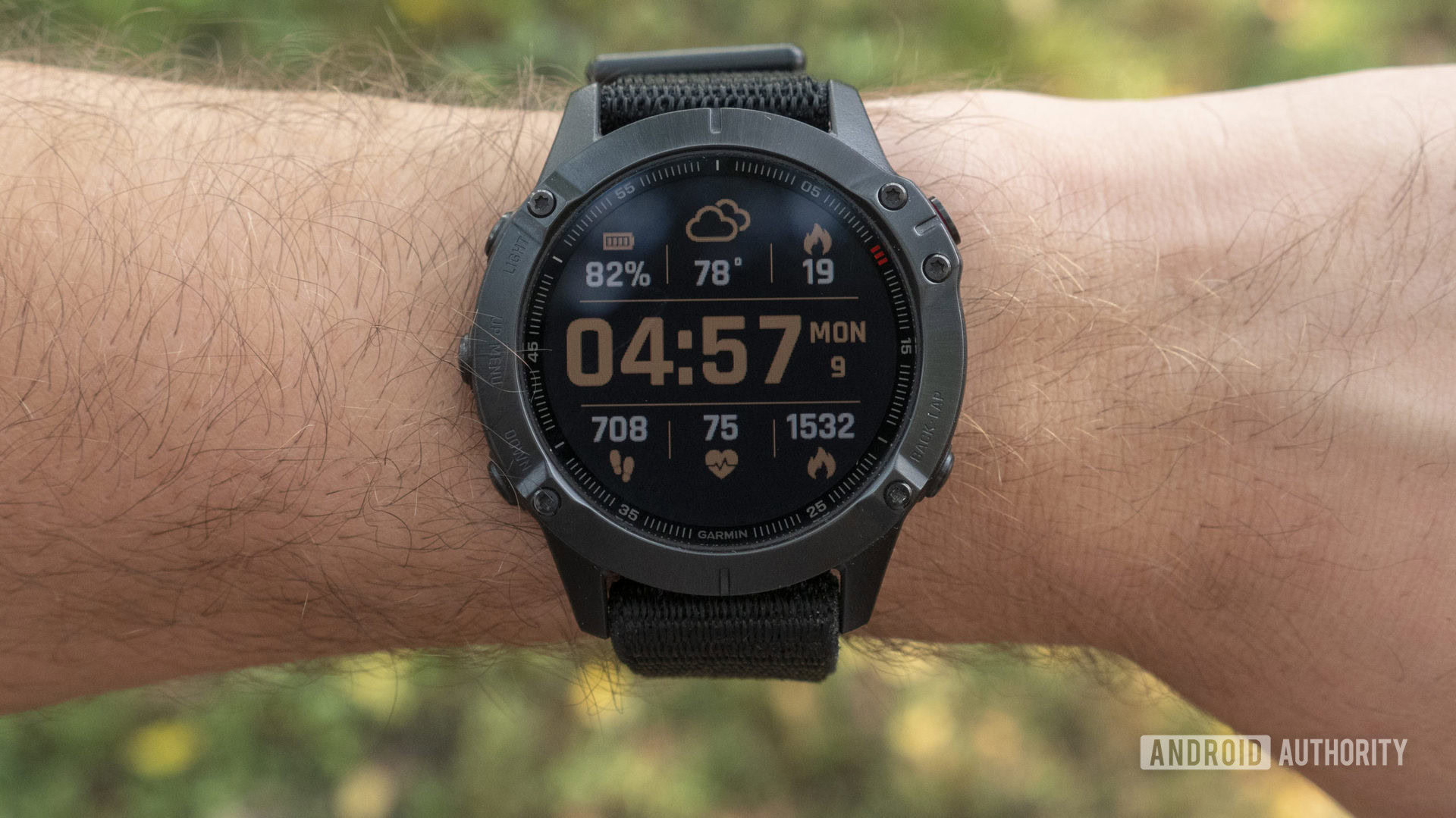 A Garmin Fenix 6 Pro on a user's wrist displays a clock face with the time, temperature, battery, and varied health and activity icons.