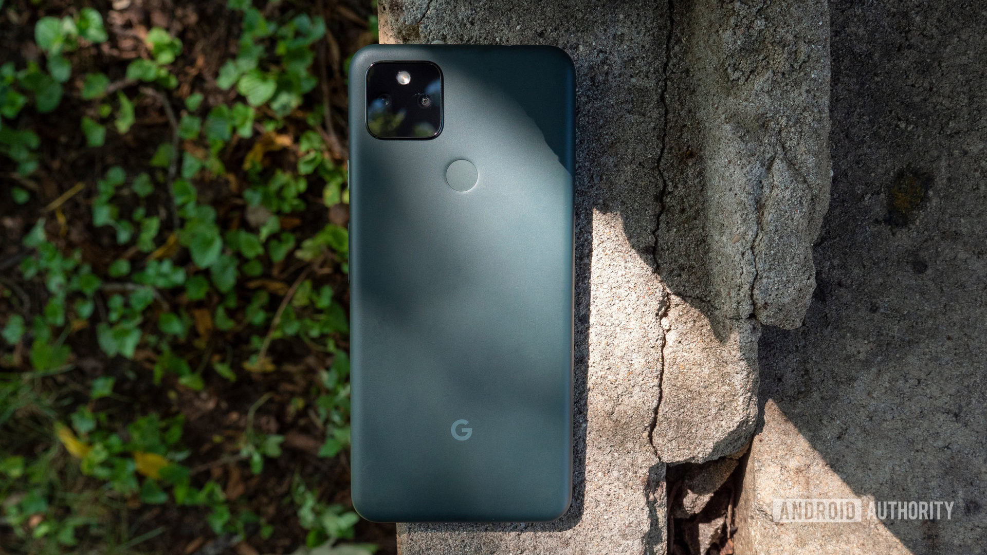 the google pixel 5a on a piece of cement showing its back in mostly black color - Phones with Night Mode