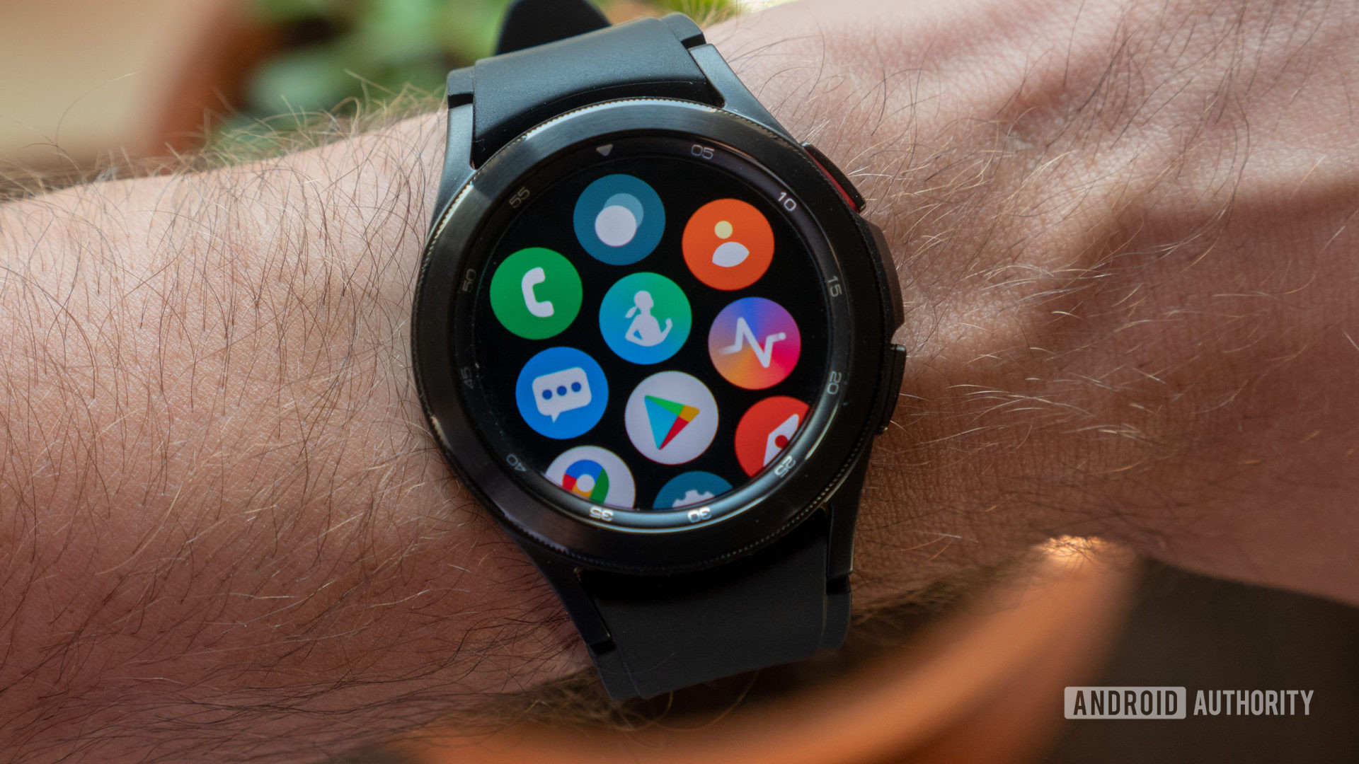 The Samsung Galaxy Watch 4 Classic on wrist showing the all apps screen containing Samsung Health, the Google Play Store, and others