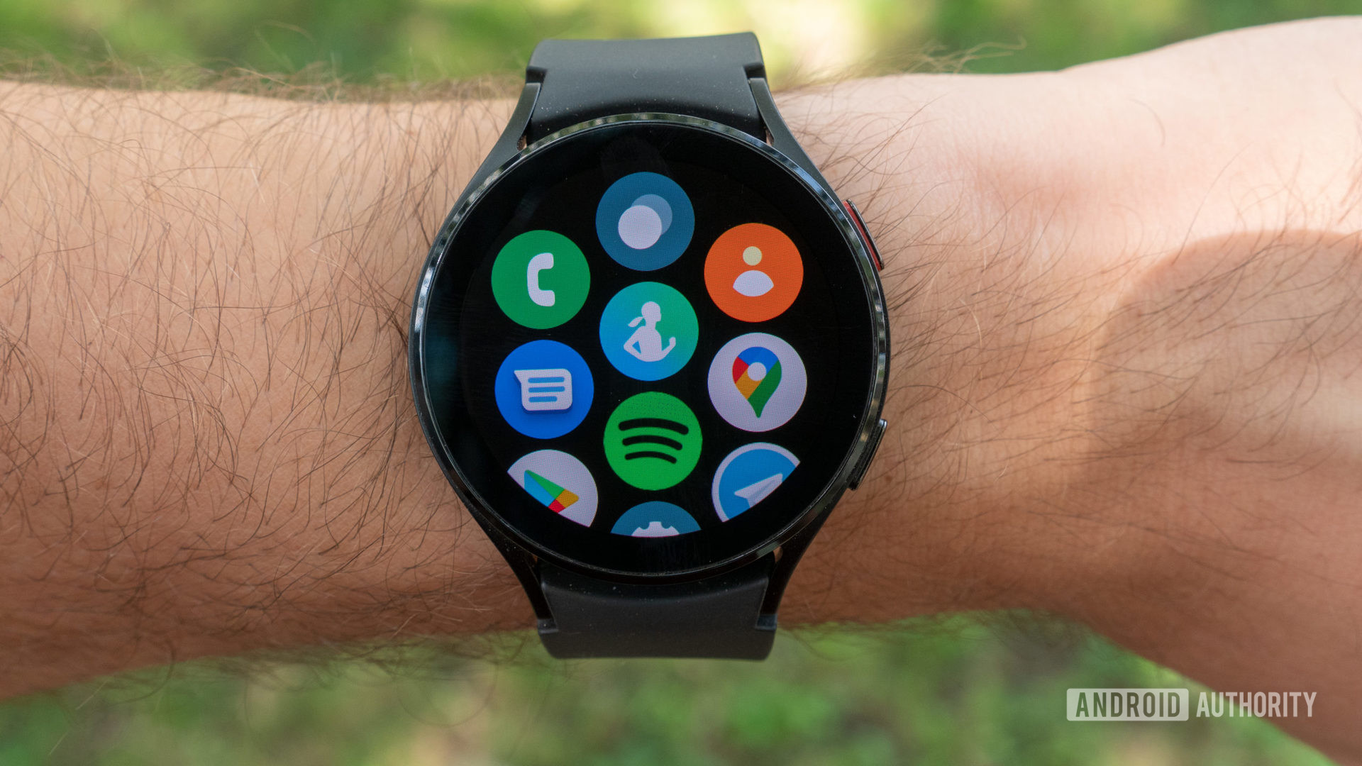 The Samsung Galaxy Watch 4 on a man's wrist showing the all-apps page.