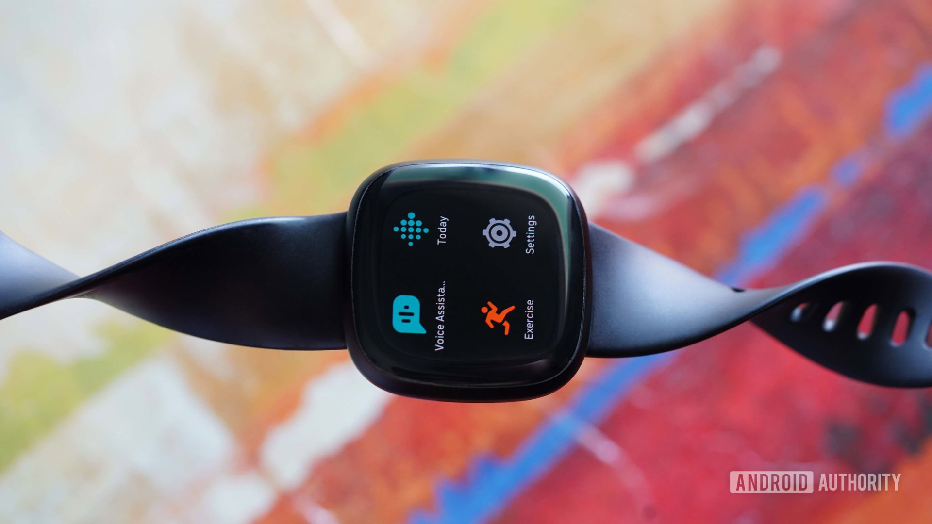 The Fitbit Versa 3 rests on an abstract, colorful background.