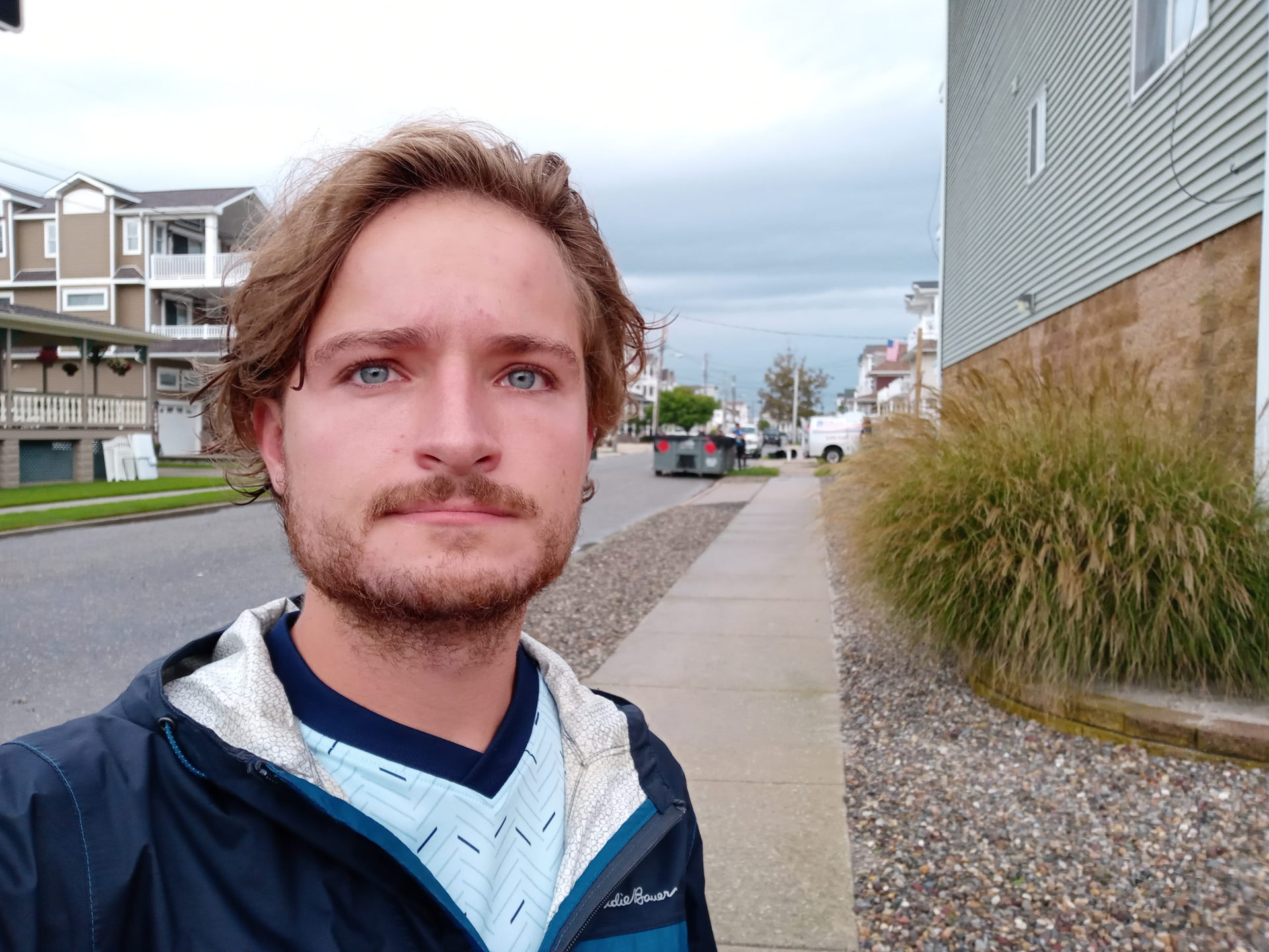 A standard selfie taken with the LG K51 showing a man with light hair and facial hair wearing a white and blue t-shirt with a blue jacket over the top.