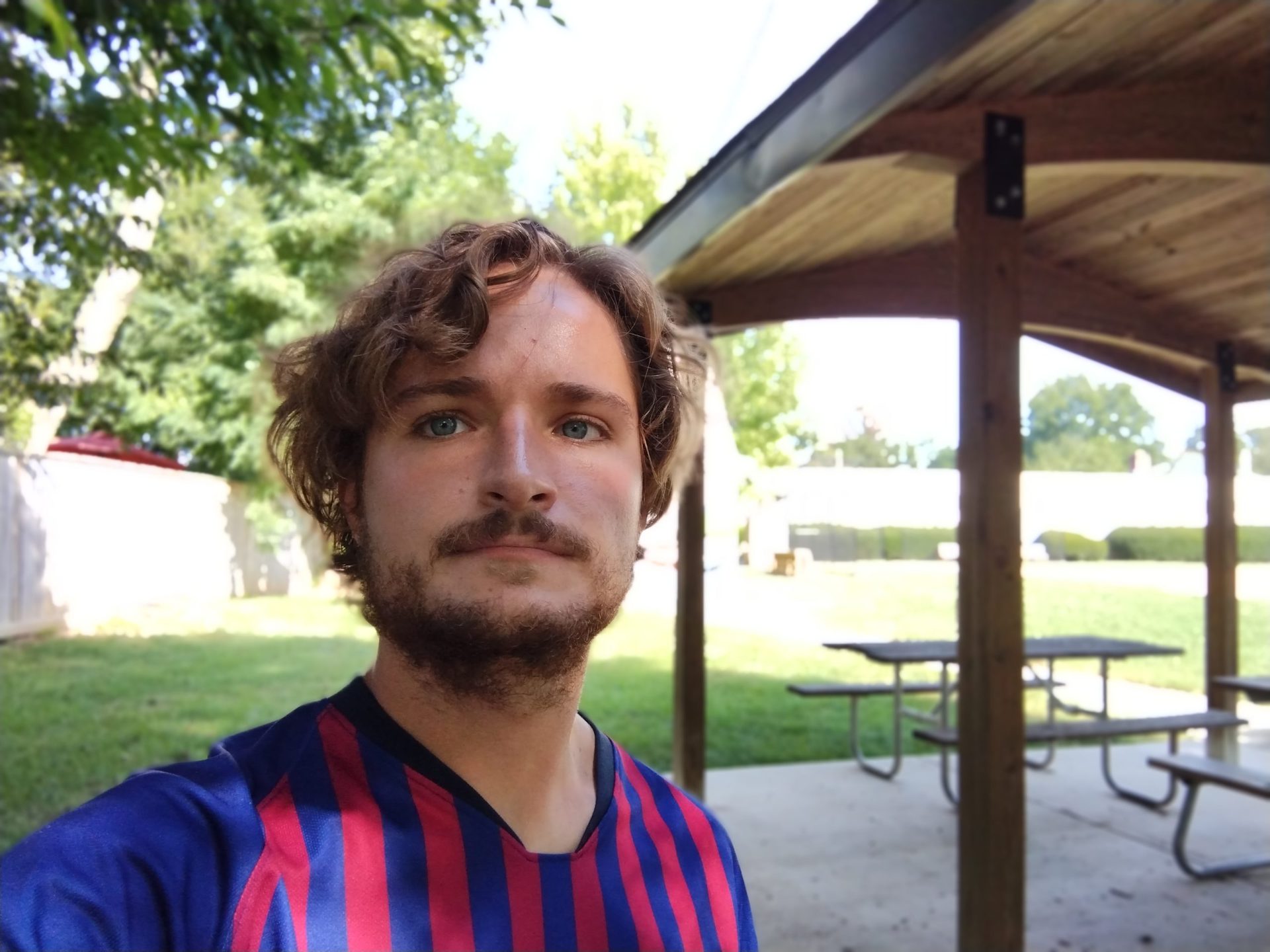 Motorola Moto G Power portrait selfie of a man with light curly hair and facial hair wearing a blue and red striped top