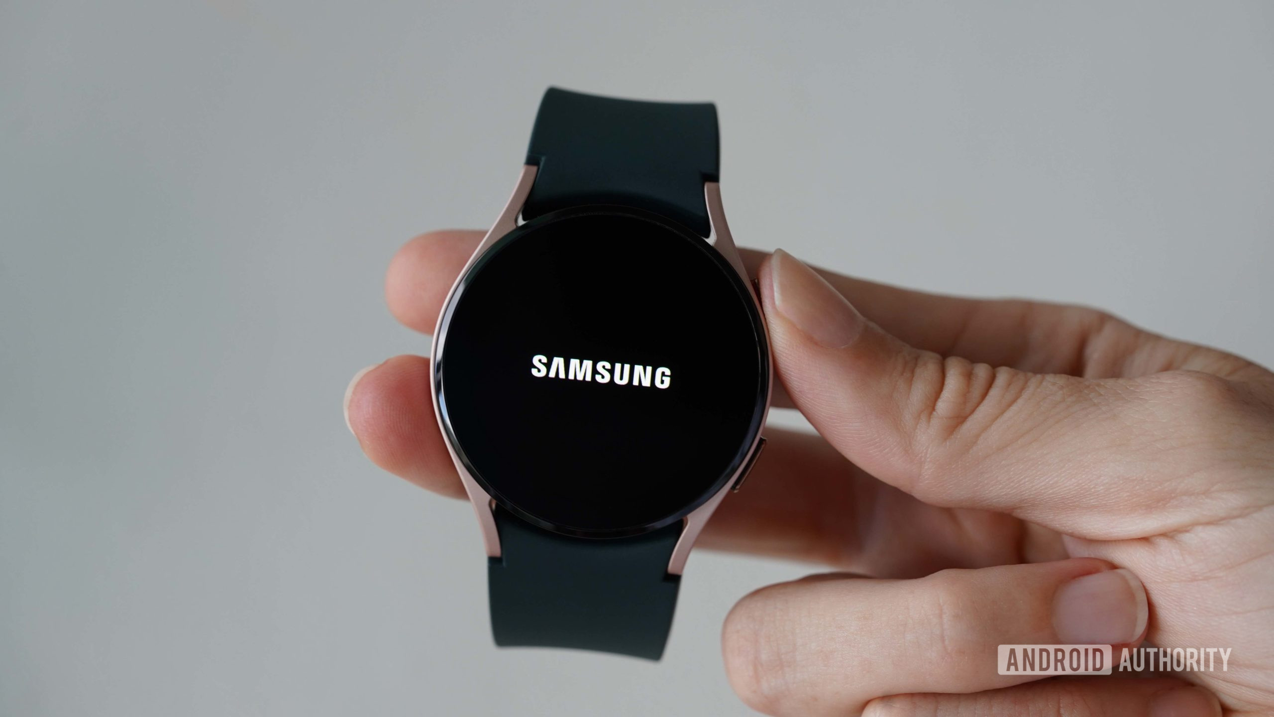 A user turns on her Samsung Galaxy Watch 4 by holding down the top button.
