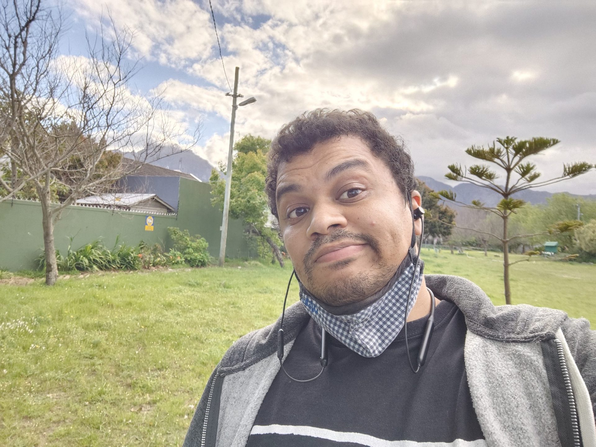 Another Vivo X70 Pro Plus selfie sample of a man with dark hair wearing a face mask down under his chin, in a t-shirt and hoodie.