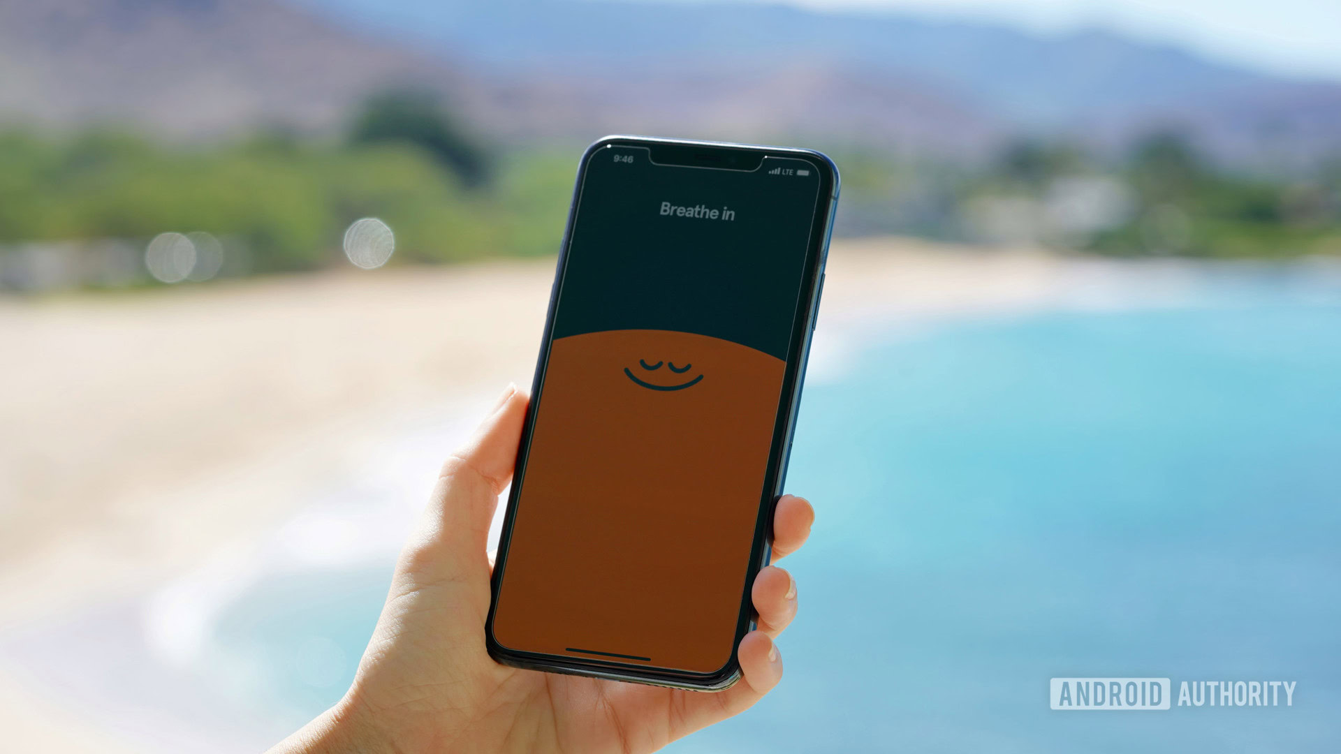 An iPhone 11 displays the Breath in, Breath out welcome sequence of the app Headspace.