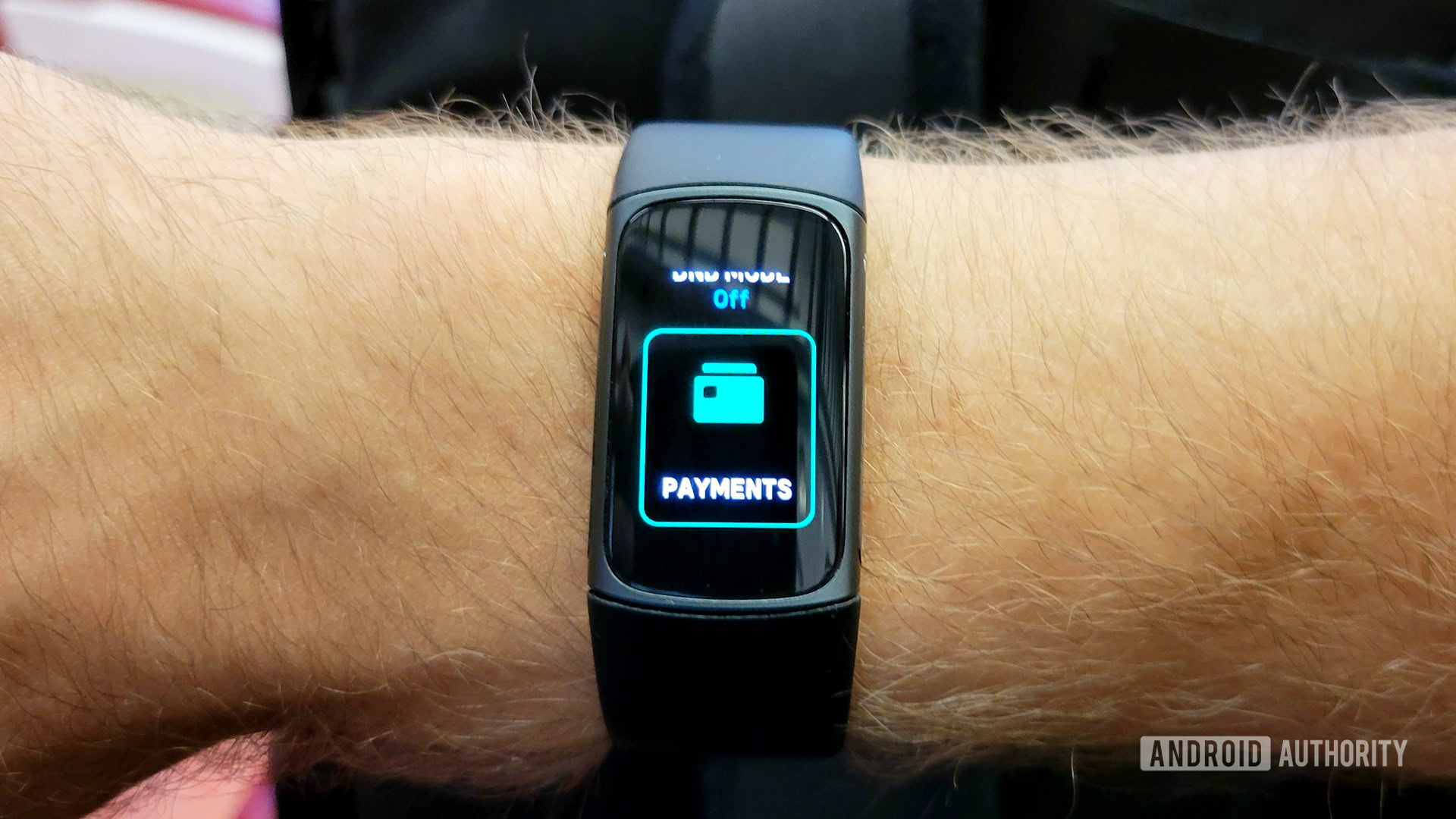 A Fitbit Charge 5 on a man's wrist displays a Fitbit Pay screen.