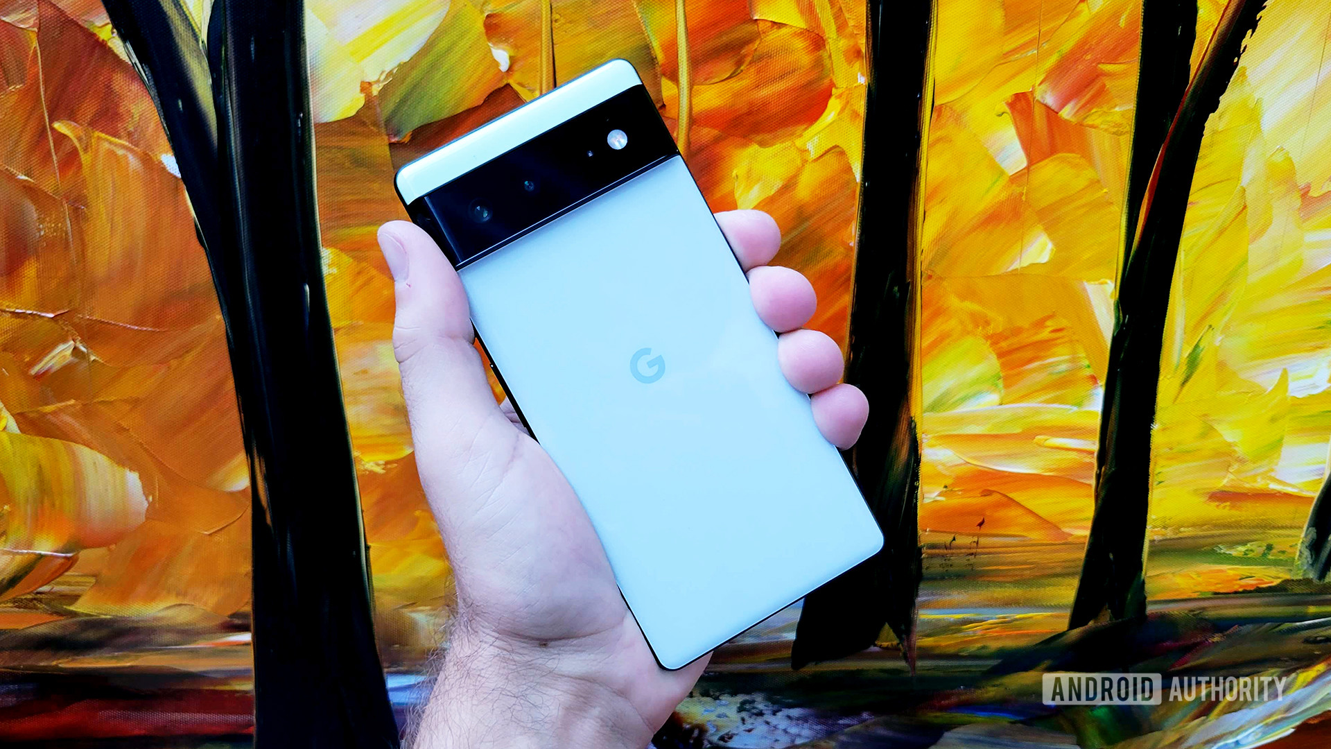 Google Pixel 6 in hand with painting behind