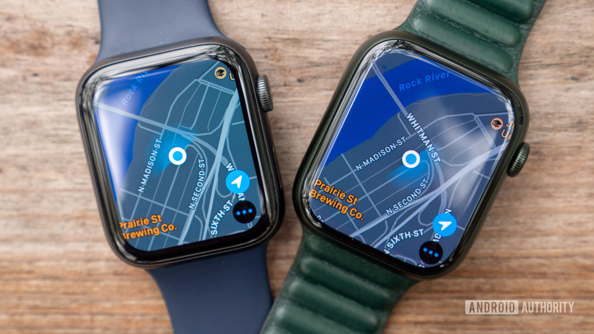 An Apple Watch Series 7 and Apple Watch Series 6 rest on a wooden table, each displaying Apple Maps on screen.