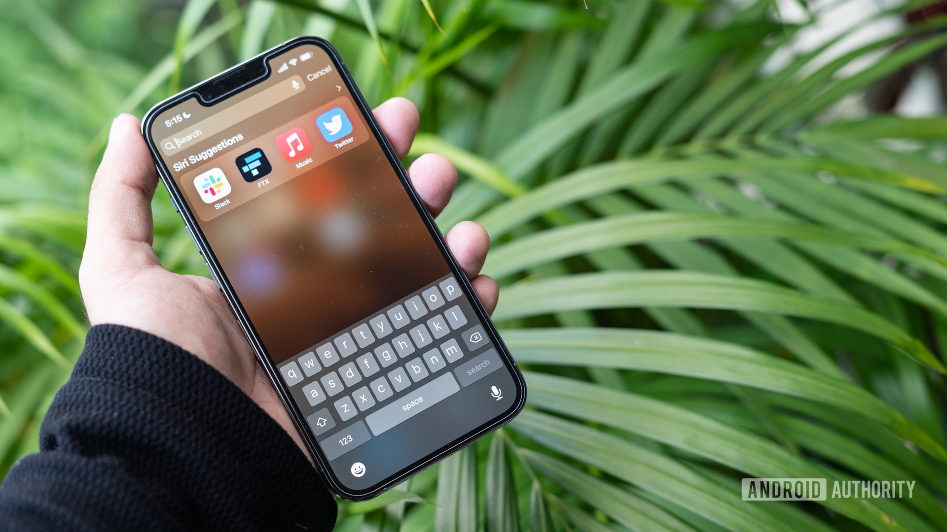 iPhone 13 Pro in hand with search and keyboard