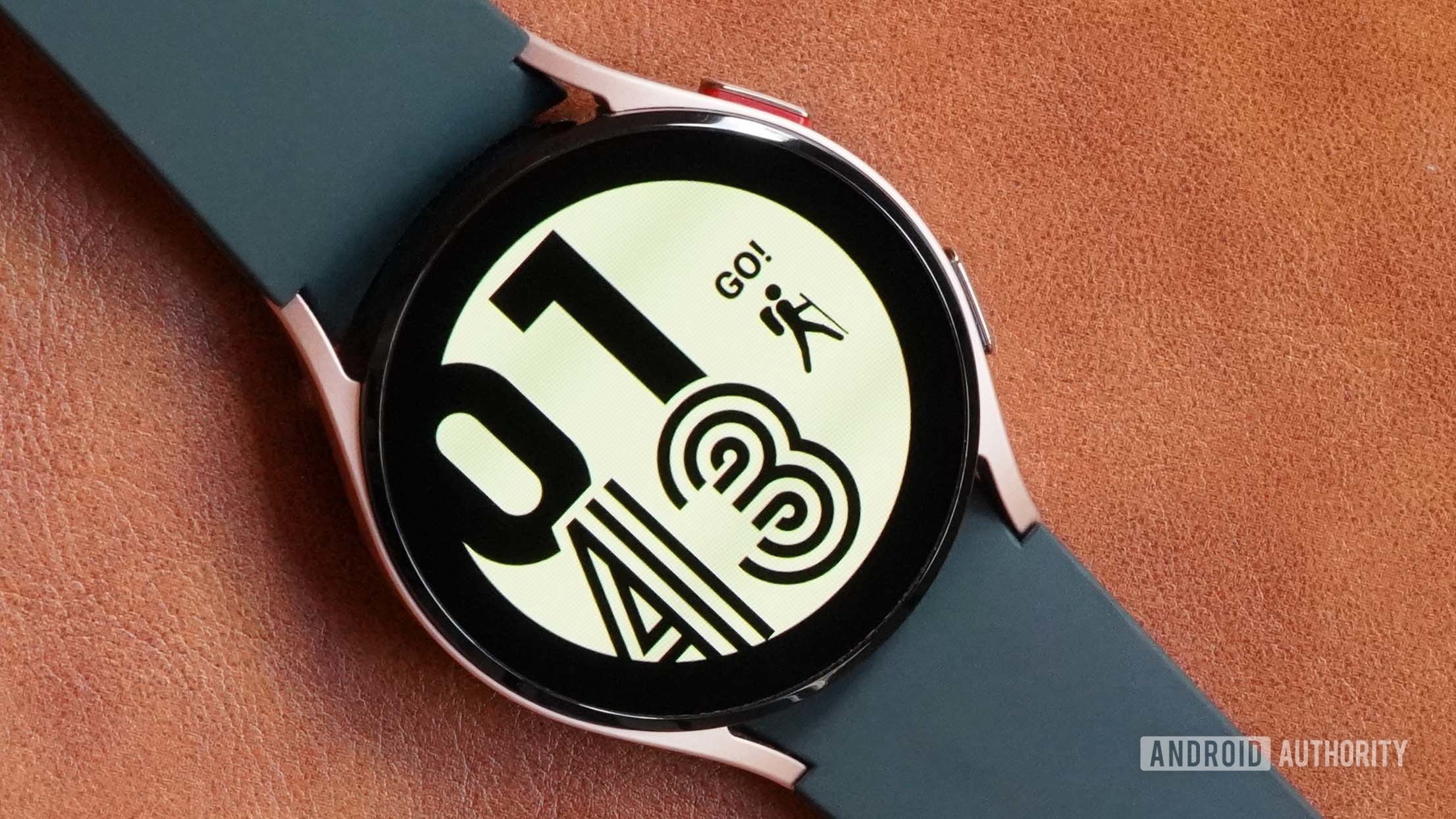 A Samsung Galaxy Watch 4 on a leather surface displays the watch face Active.