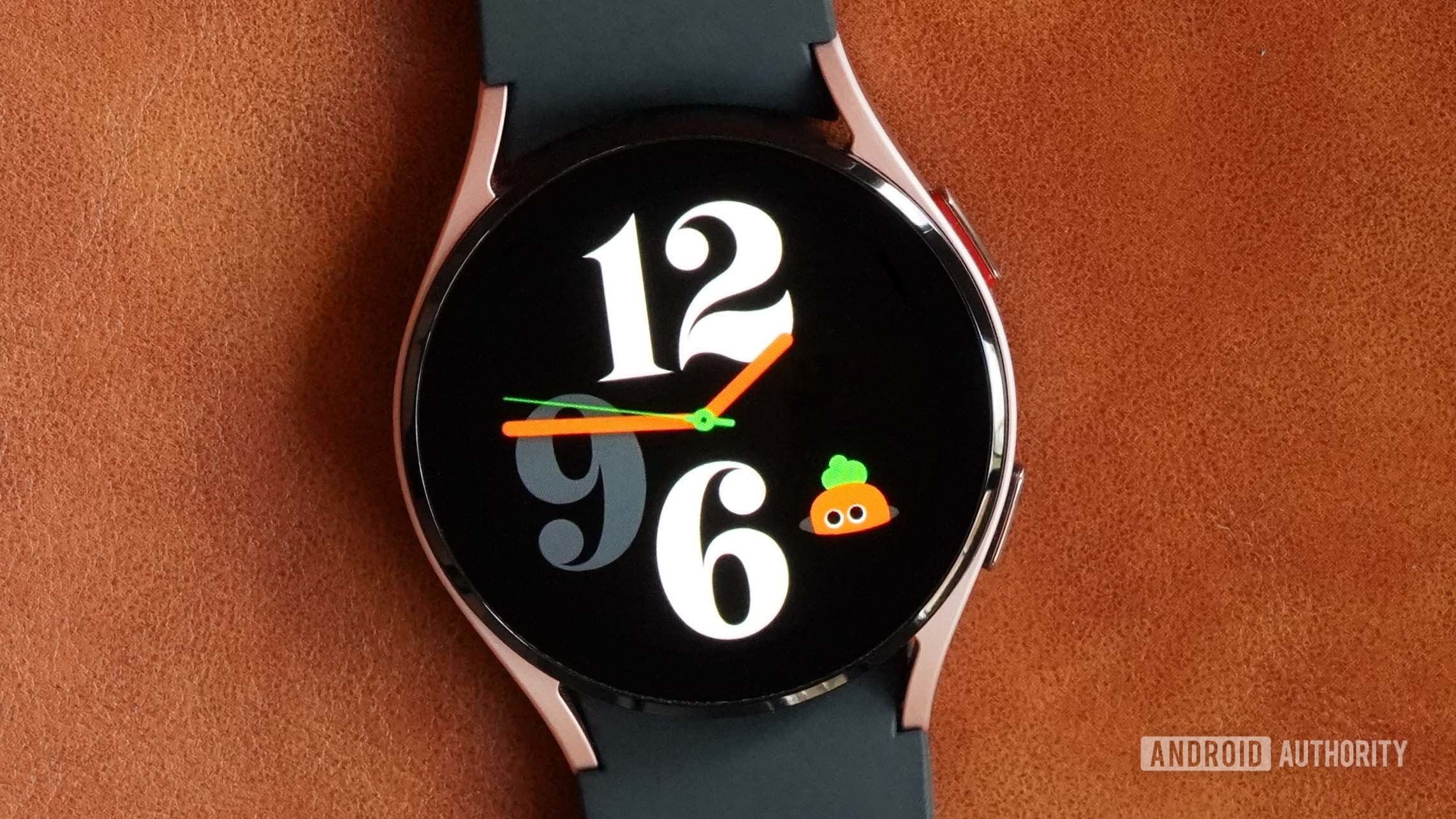A Samsung Galaxy Watch 4 on a leather surface displays the watch face Cute Character.