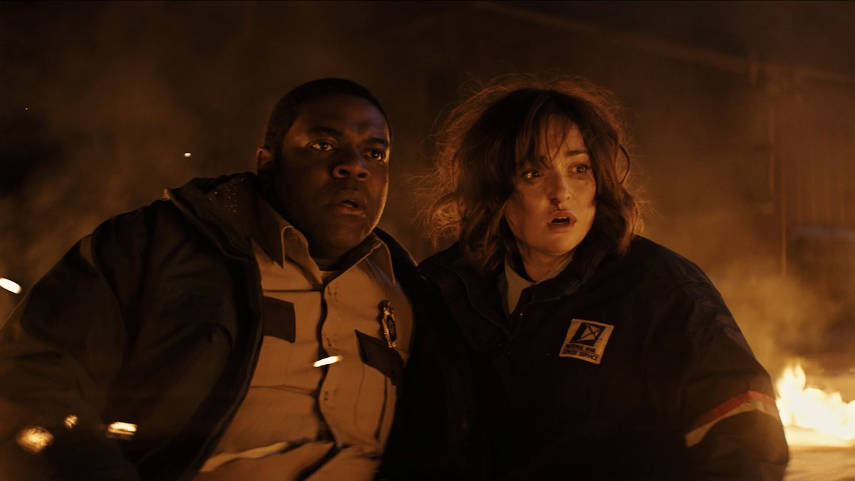 Sam Richardson and Milana Vayntrub sit in the snow, surrounded in flames, in Werewolves Within - best showtime movies