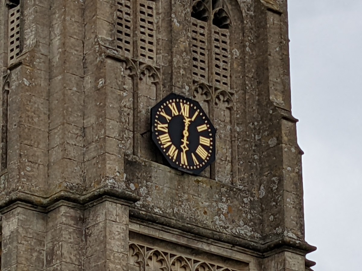 7x zoom shot of stone church tower and its black and gold clock, on an overcast day shot on Google Pixel 5