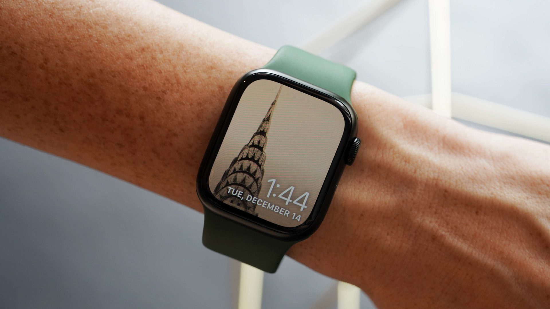 An Apple Watch Series 7 on a user's wrist displays an image of the Chrysler building in their Photo watch face.