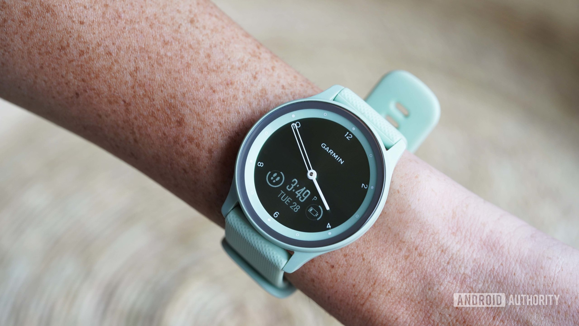 A user activates the &quot;hidden&quot; display on her soft green Garmin Vivomove Sport, Garmin best hybrid smartwatch.